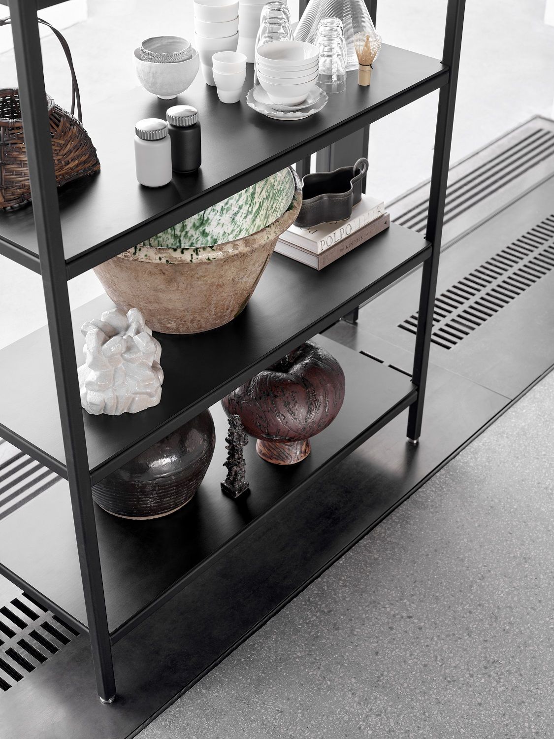 Hochauflösendes Bild eines schwarzen, hohen Regalsystems von Vipp, gefüllt mit Deko-Objekten und Geschirr.