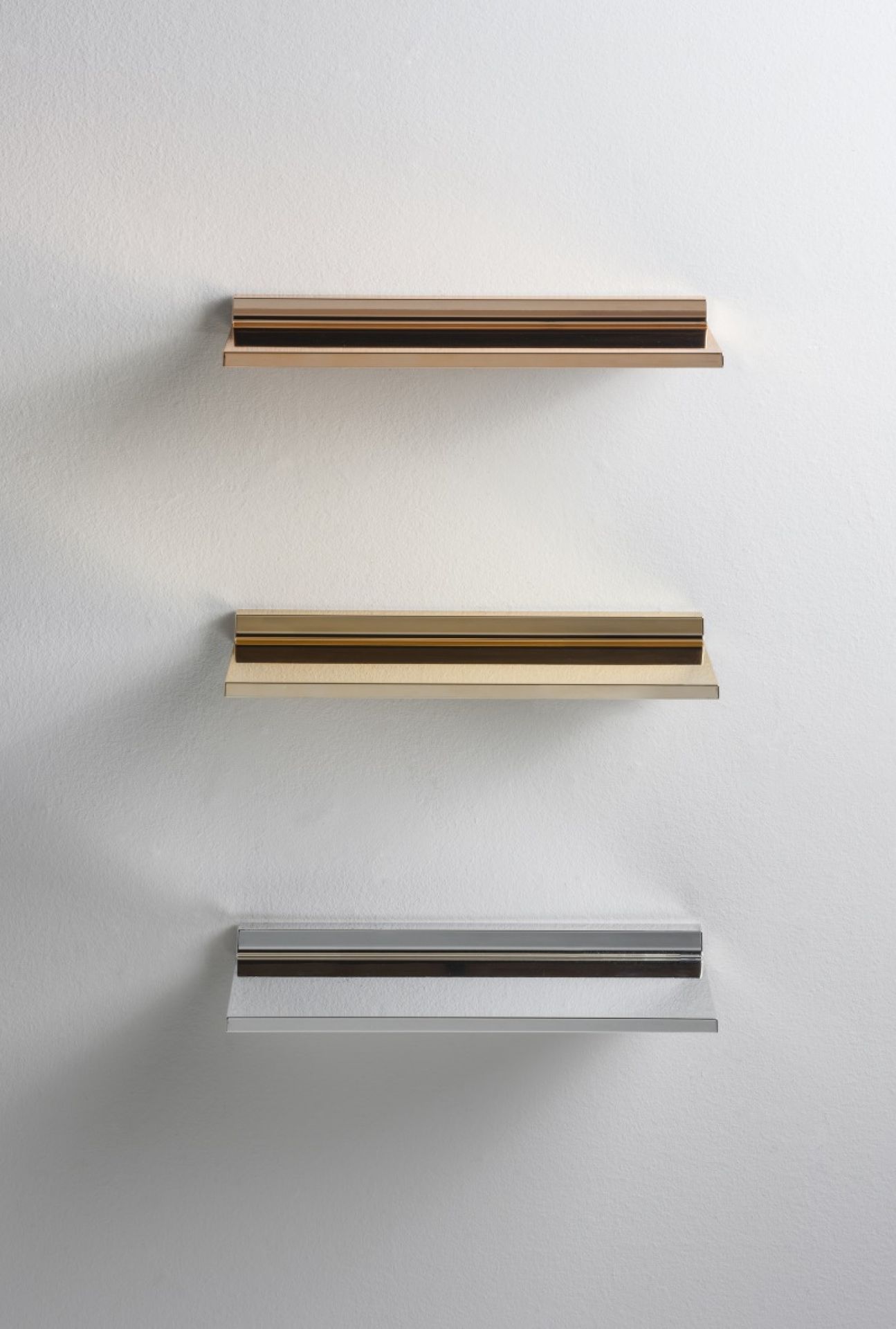Drei Shelfish Regale von Kartell in Gold, Silber und Kupfer an einer weißen Wand.