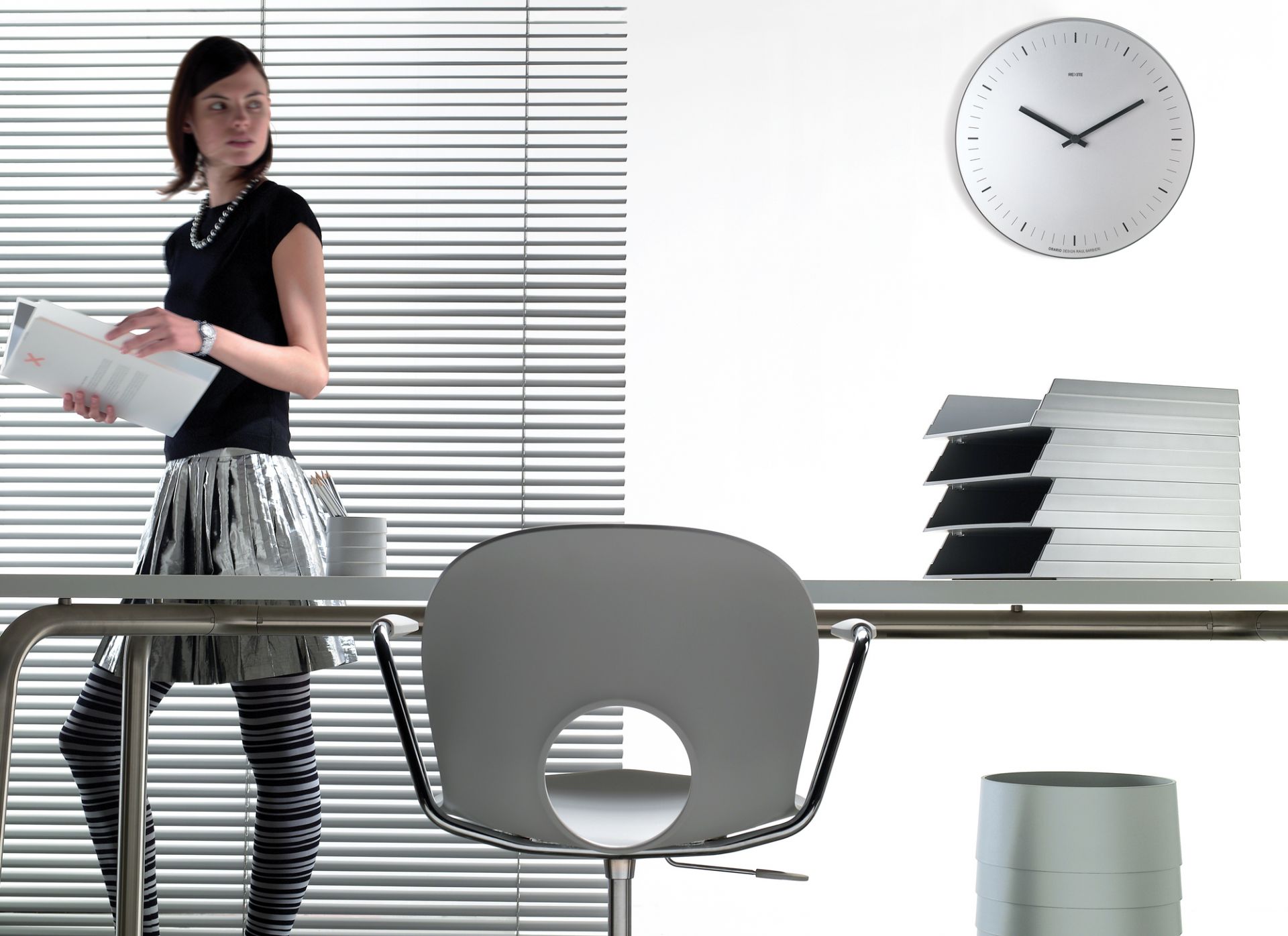 Helle Büroszene mit Orario Wanduhr von Rexite, Edelstahl, ohne Ziffern, modernes Design.