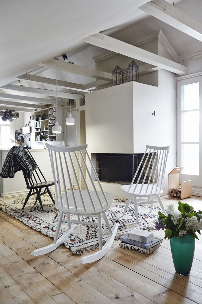 Heller Wohnraum mit Artek Schaukelstuhl Mademoiselle, skandinavisches Design, weiß lackiert, gemütliche Atmosphäre.