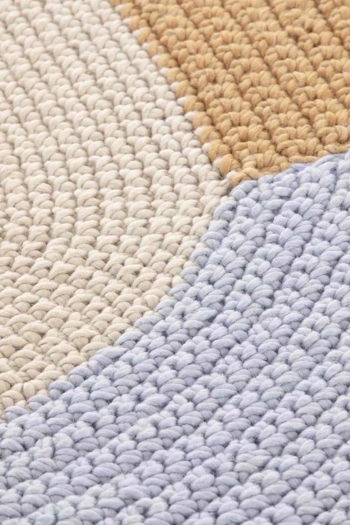 Detailaufnahme des The Crochet Collection Teppichs in Beige, handgefertigt mit auffälliger Häkel-Optik und Textur.