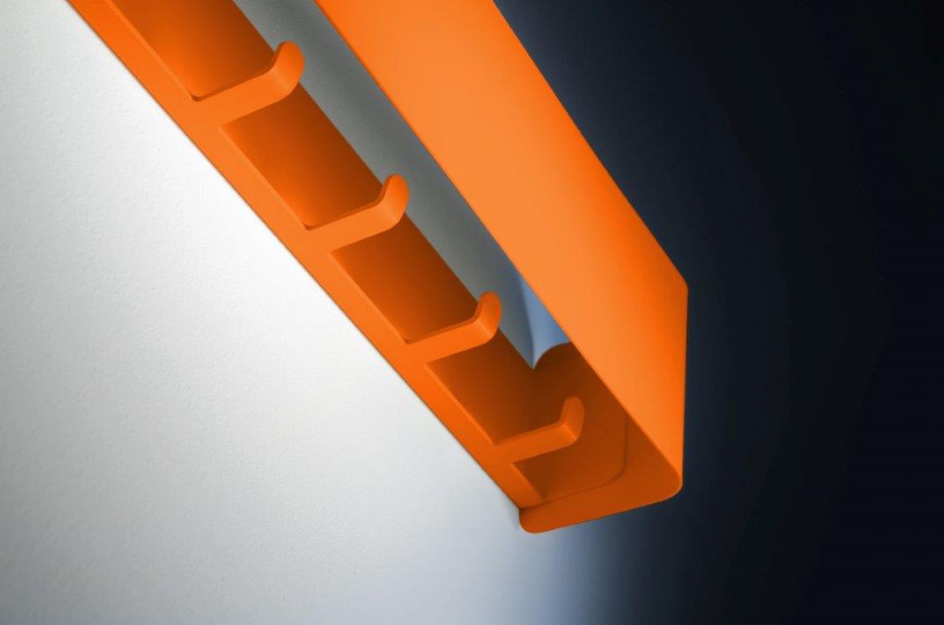 Orangefarbene Radius Garderobe mit fünf Haken an einer weißen Wand. Moderne Wandgarderobe.