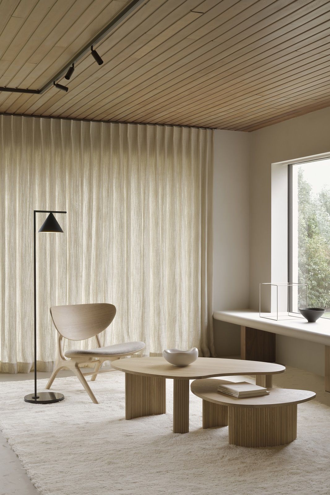 Zwei Ethnicraft Couchtische in Kieselform aus hellem Holz in einem Wohnzimmer.