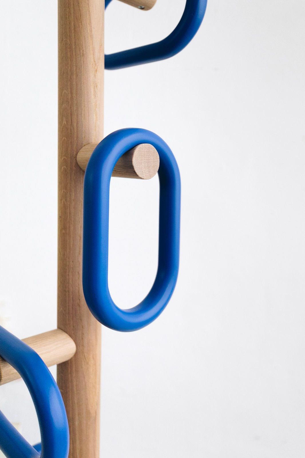 Nahaufnahme des Hartô Kleiderständers mit blauen Aufhängern und hellem Holz, moderner Garderobenständer.