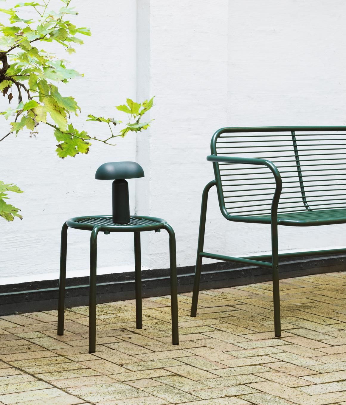 Normann Copenhagen Vig Stool Hocker für den Außenbereich, dunkelgrün, mit passender Bank im Garten.
