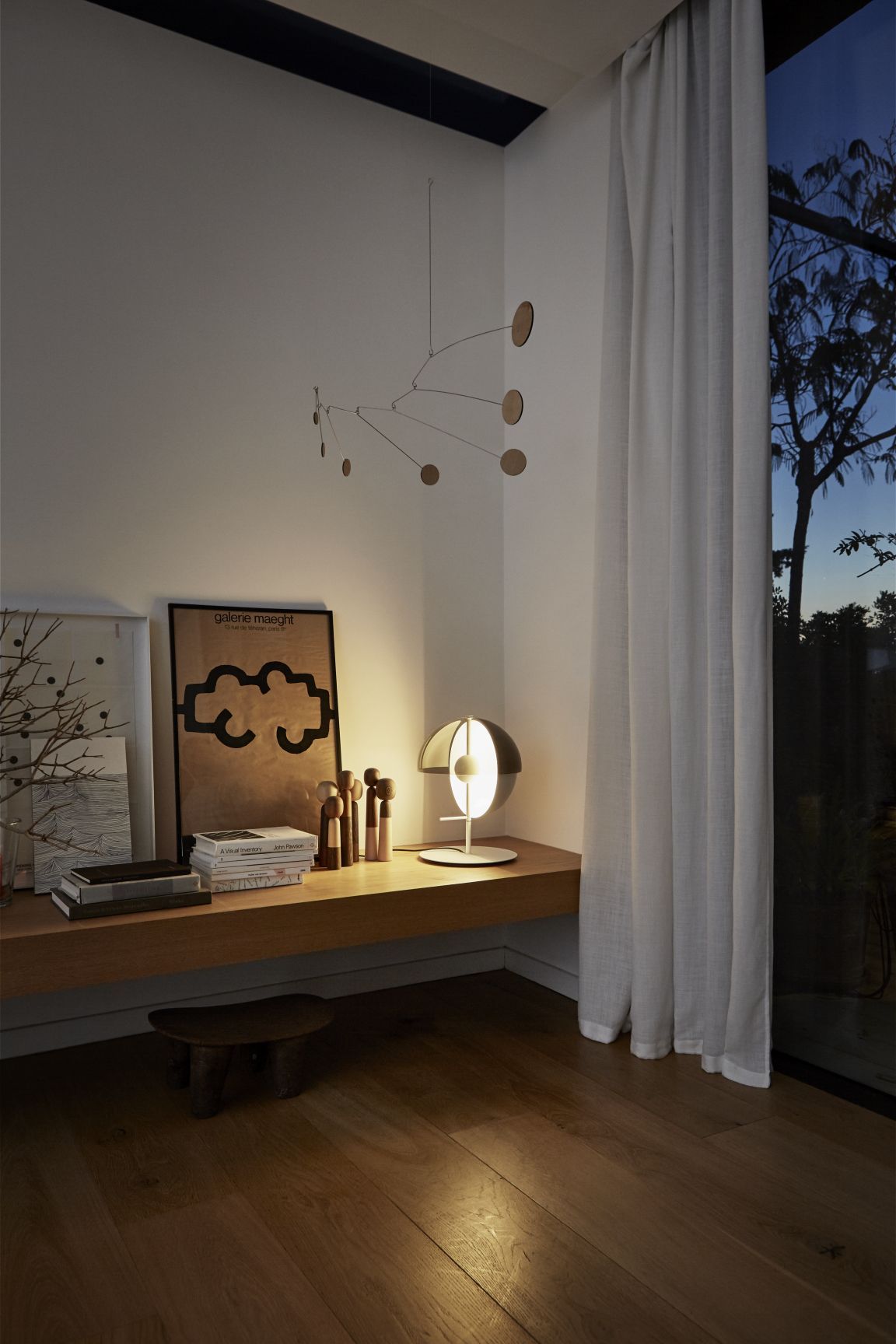 Theia M Tischleuchte schwarz von Marset auf einem Holzregal in einem stilvollen Interieur.