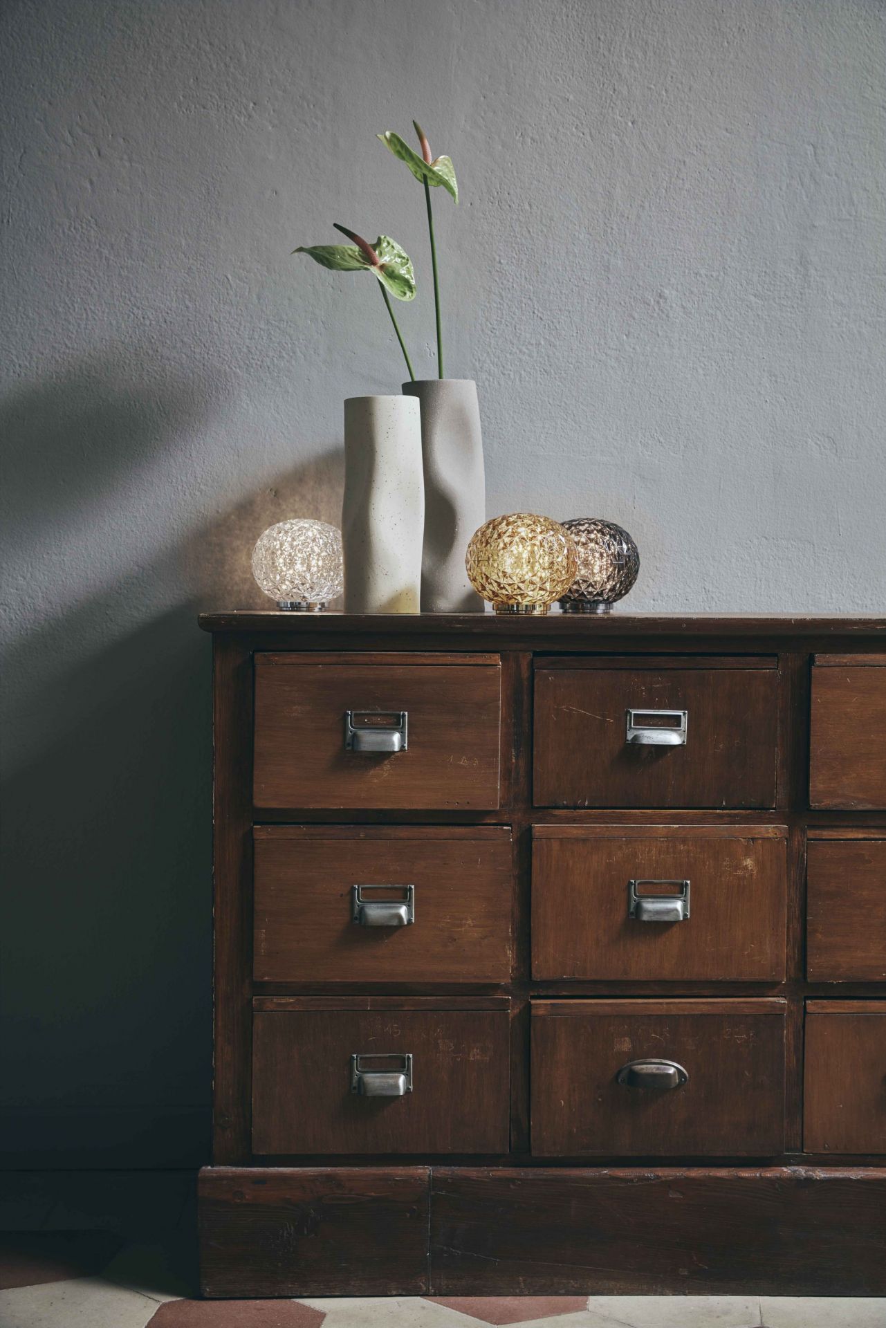 Gelbe Mini Planet LED Tischleuchte von Kartell auf Kommode mit Vasen. Akku-betriebene Lampe.