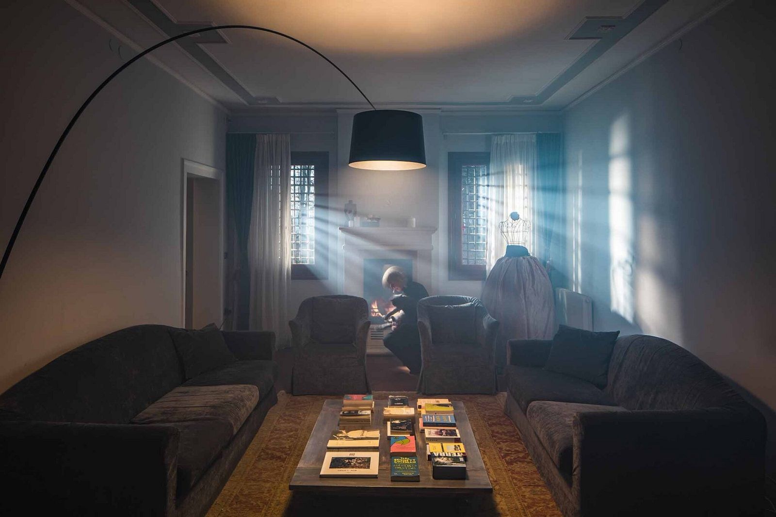 Graphitfarbene Twiggy Elle Terra LED Stehleuchte von Foscarini beleuchtet stilvoll ein Wohnzimmer mit Kamin.