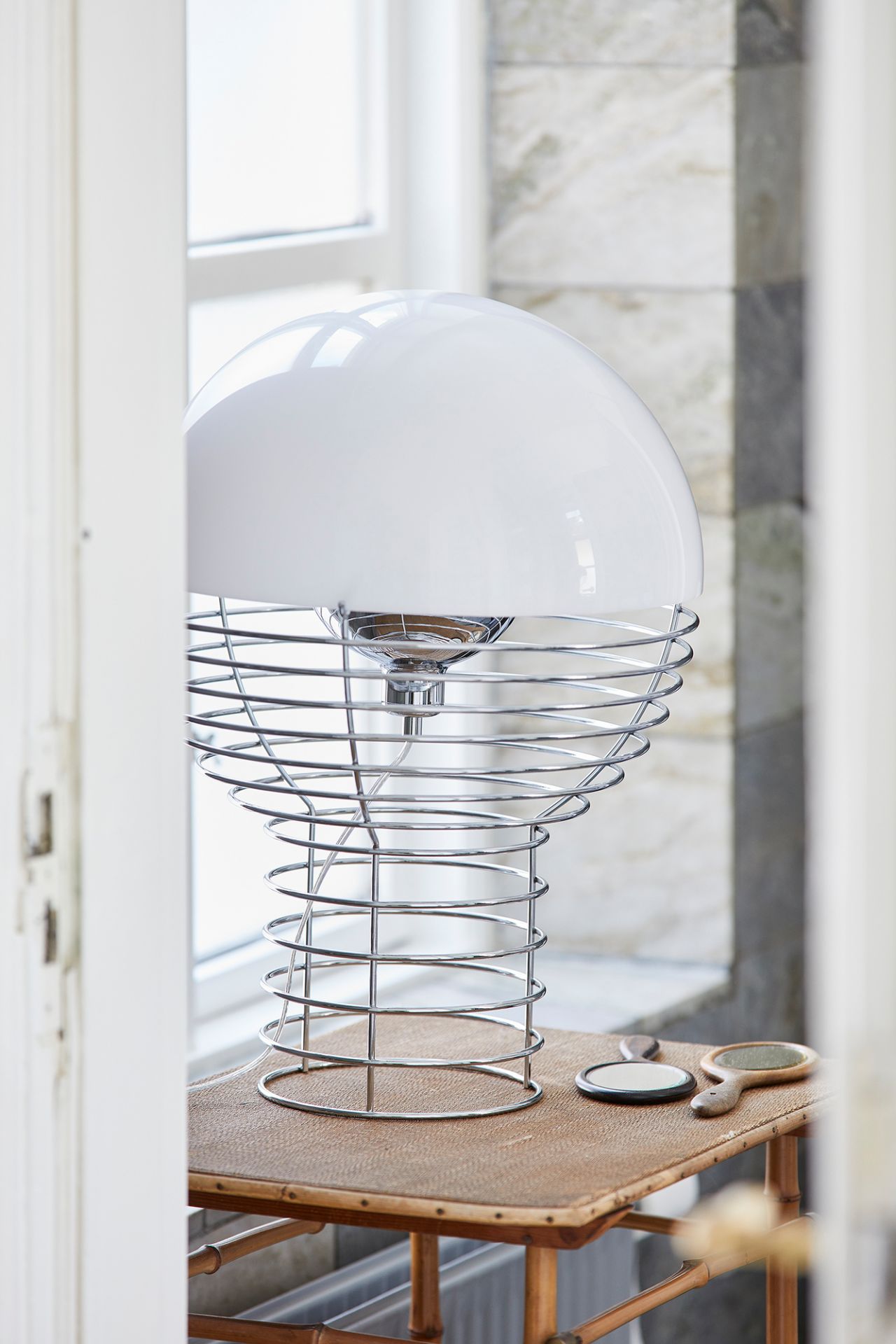 Verpan Wire Large Tischleuchte mit weißem Schirm und verchromtem Drahtgestell auf einem Holztisch.