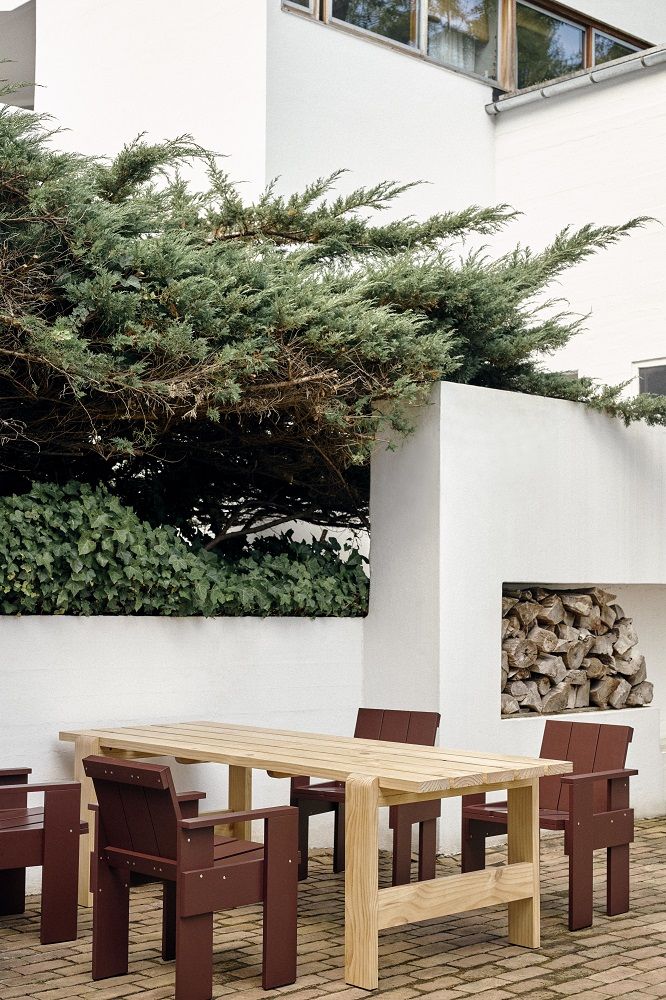 Heller Holztisch mit braunen Hay Crate Dining Chair Outdoor Stühlen im Gartenbereich.