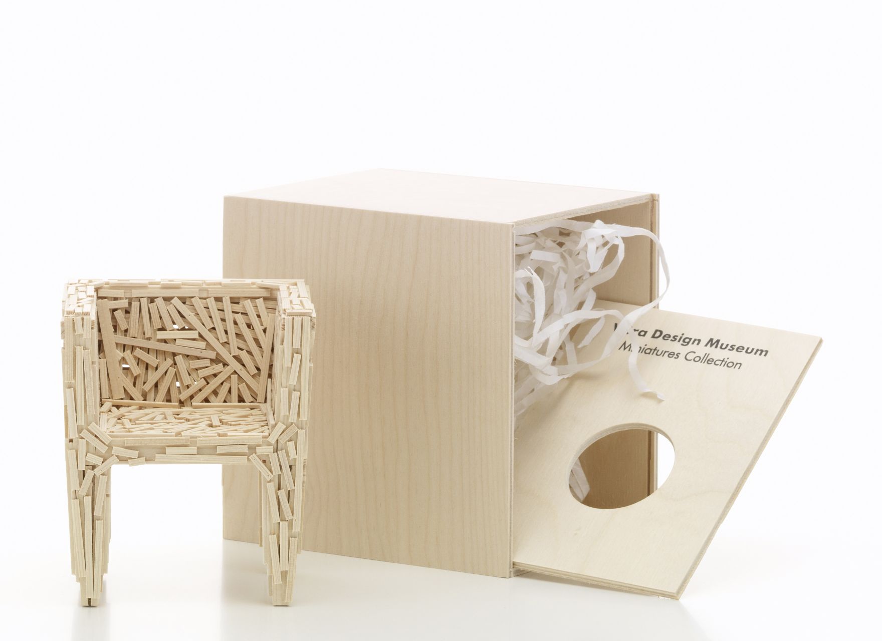 Favela Miniatur Sessel von Vitra neben geöffneter Holzbox mit Füllmaterial, Designmöbel Miniatur.