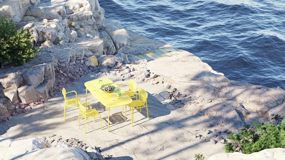 Gelber Petite Friture Week-End Rectangle Tisch mit Stühlen auf felsiger Terrasse am Meer.