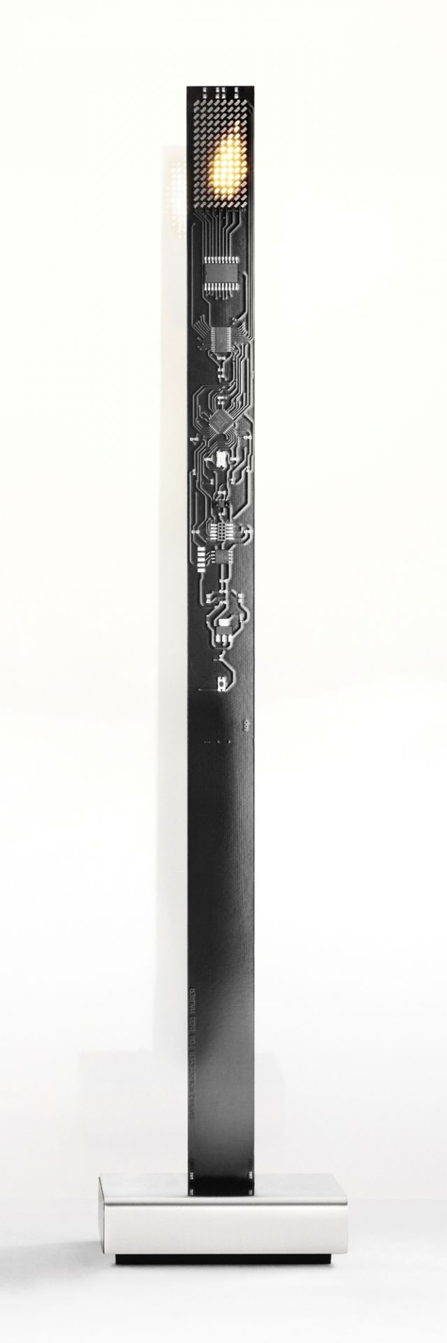 My New Flame Tischleuchte von Ingo Maurer: Schwarze Platine mit LED-Flamme auf silbernem Sockel.