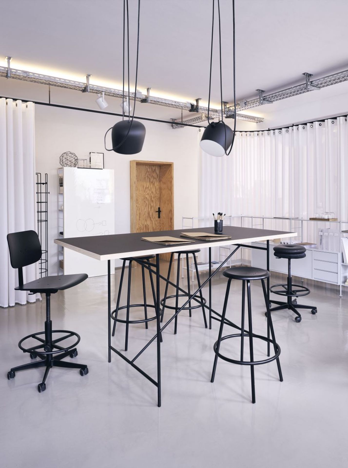 Milla Stehtisch von Richard Lampert mit schwarzen Barhockern in einem modernen Büro.