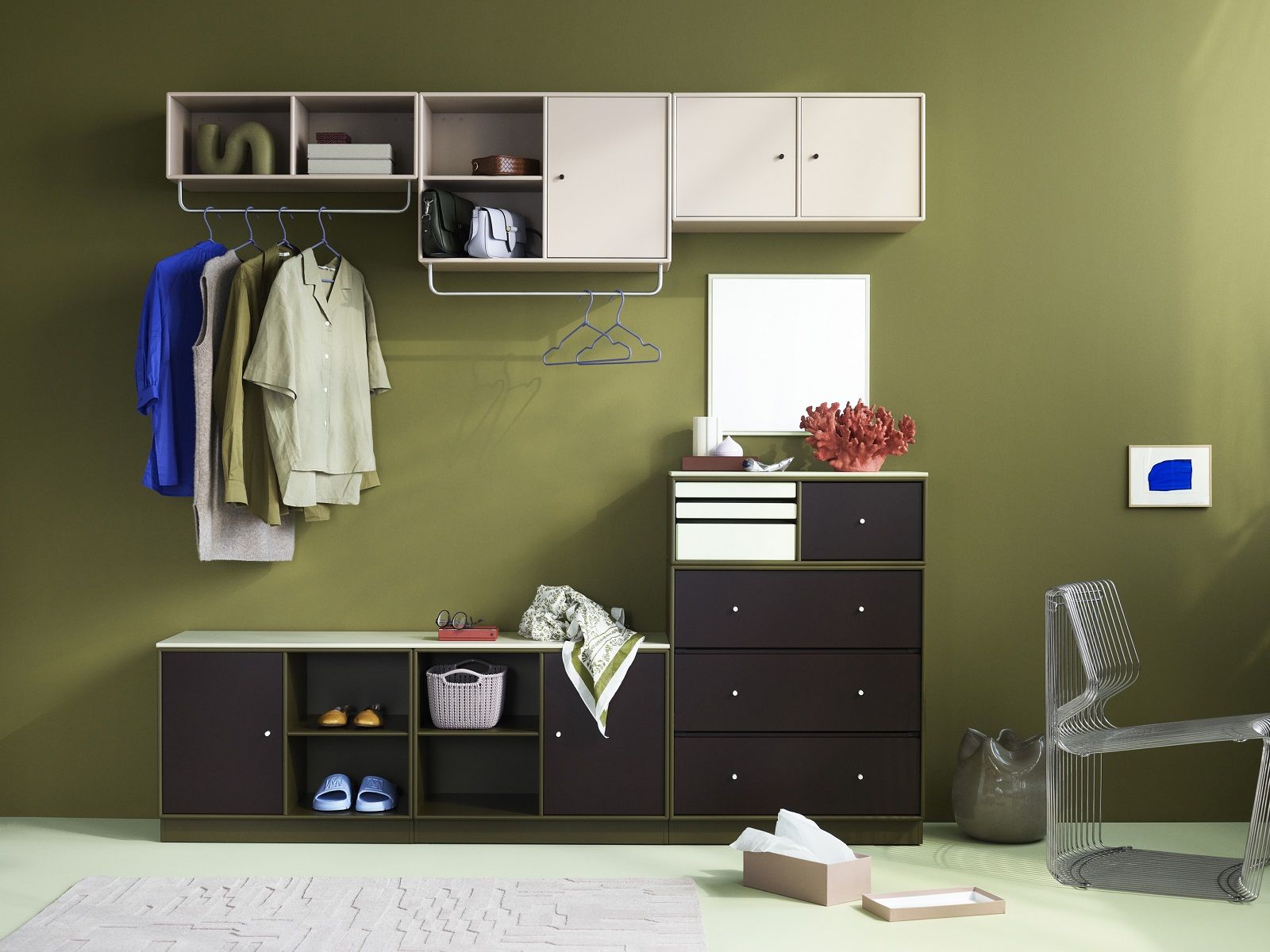 Raumansicht mit Montana Regalsystem, Kommode, Kleiderstange und Pantonova Drahtstuhl in Silber vor olivgrüner Wand.