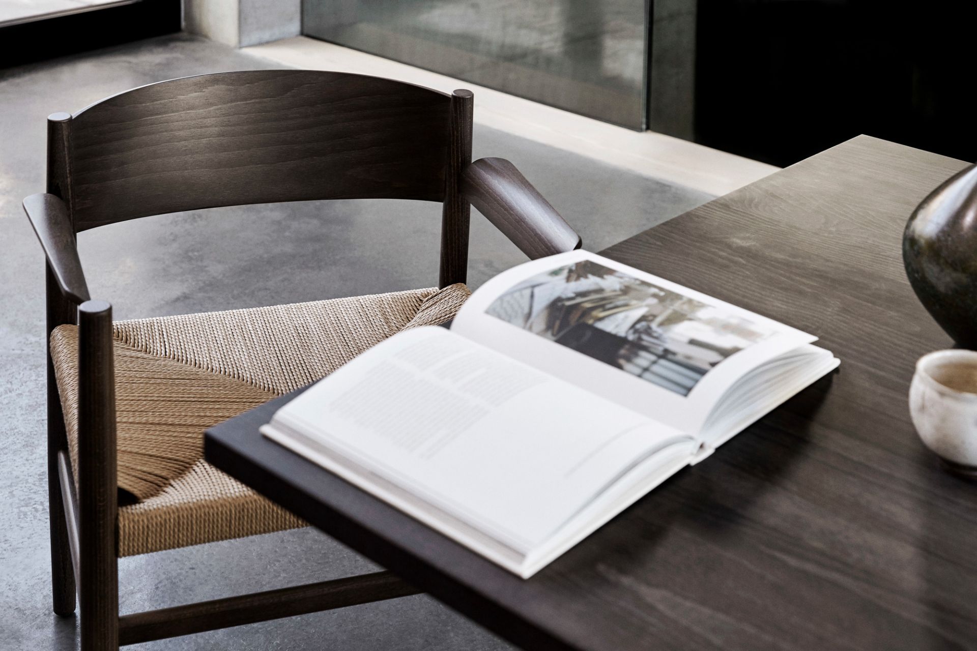 Detailaufnahme: Mater Esstisch aus dunklem Holz mit Stuhl und offenem Buch. Modernes Design.