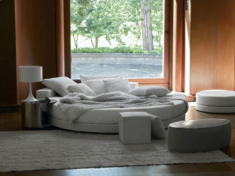 Helle Spun Light T1 Tischleuchte von Flos neben einem runden Bett im modernen Interieur.