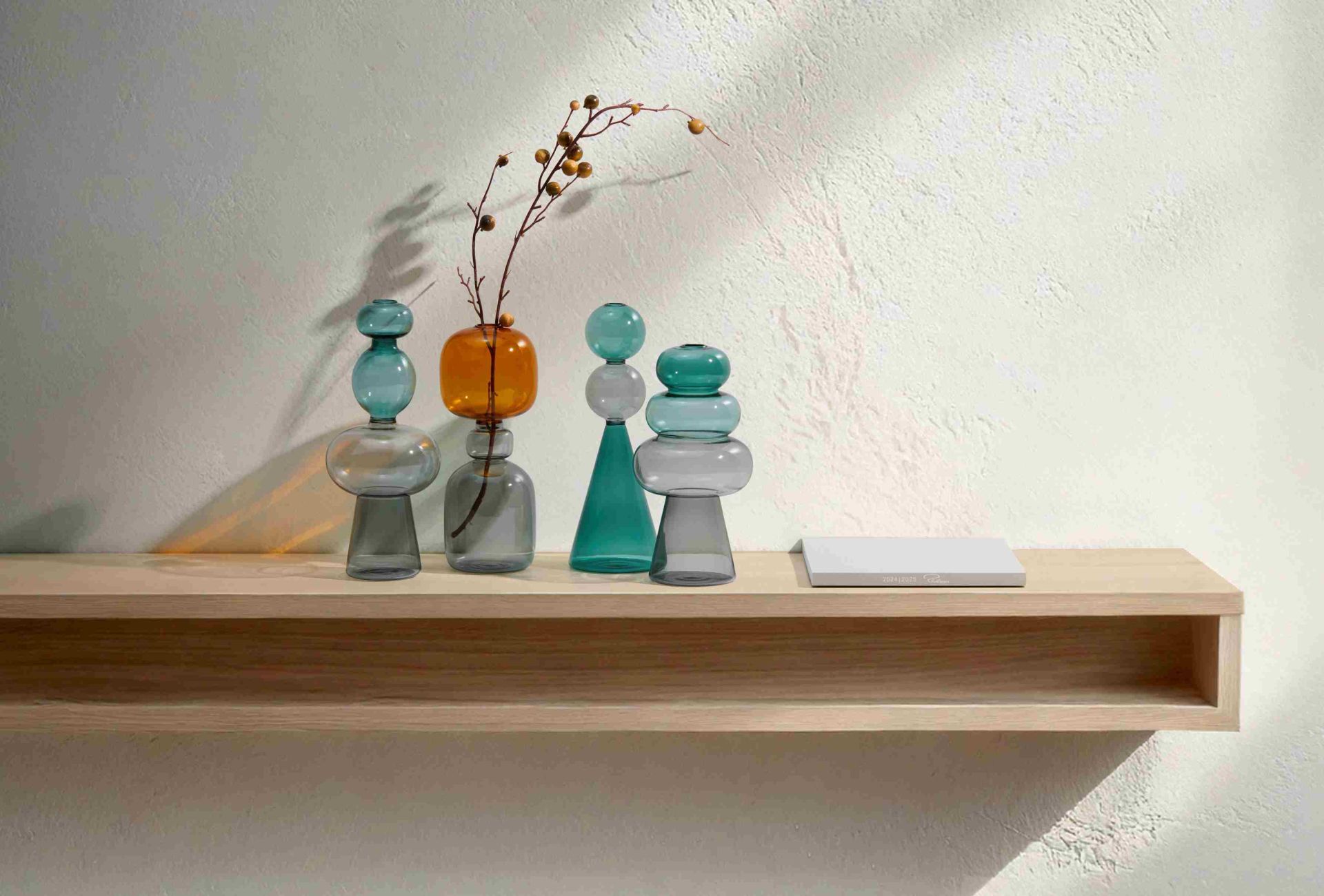 Curiosa Vase von Philippi: Mehrfarbige Glasvasen in Sanduhr-Form auf einem Holzregal. Dekorative Wohnaccessoires.