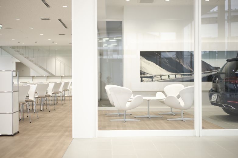 Heller Raum mit weißen Schwanenstühlen und einem kleinen, rechteckigen Tisch. Fritz Hansen Möbel im modernen Design.