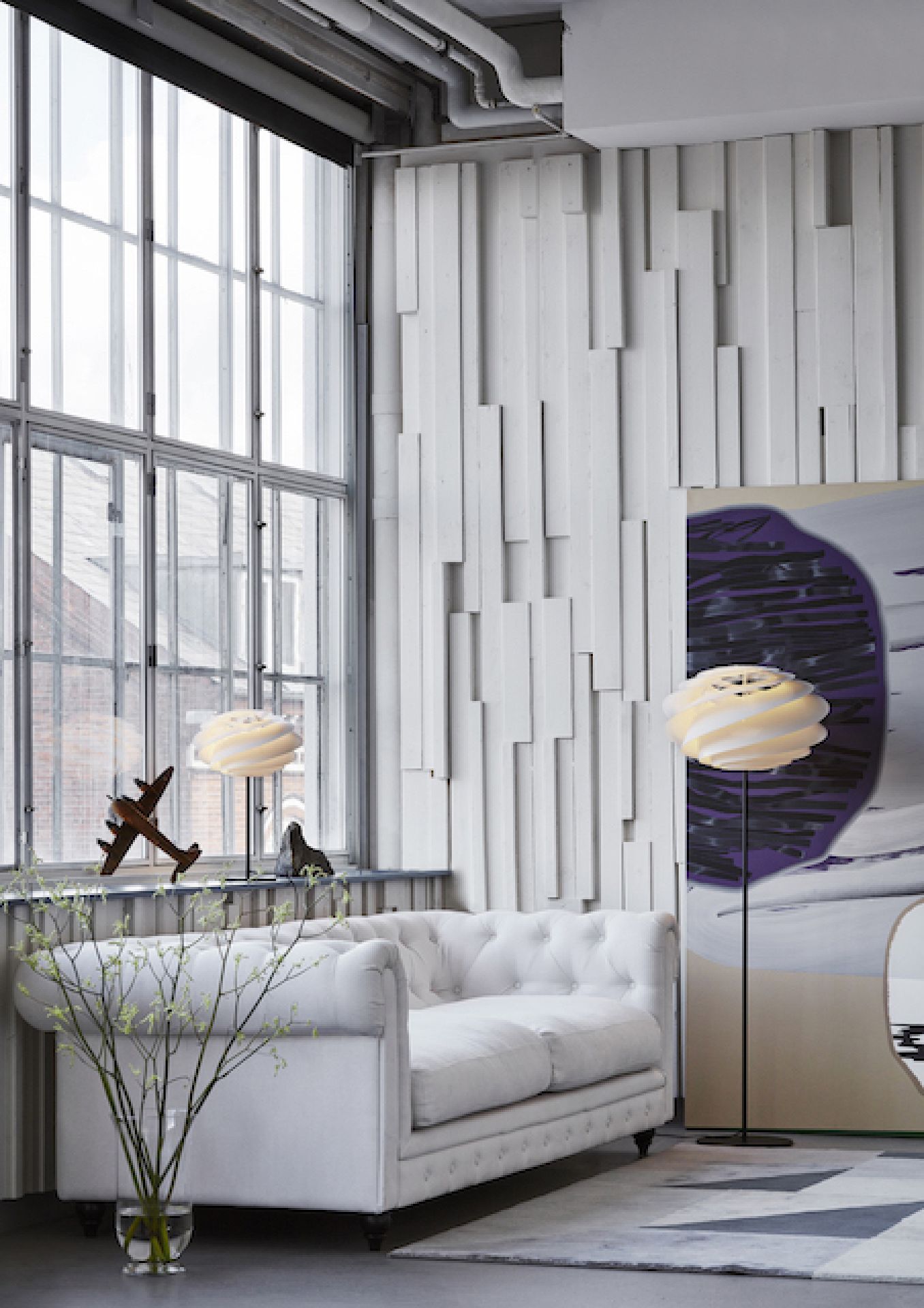 Swirl Stehleuchte von Le Klint in modernem Wohnzimmer mit Sofa und großem Fenster.