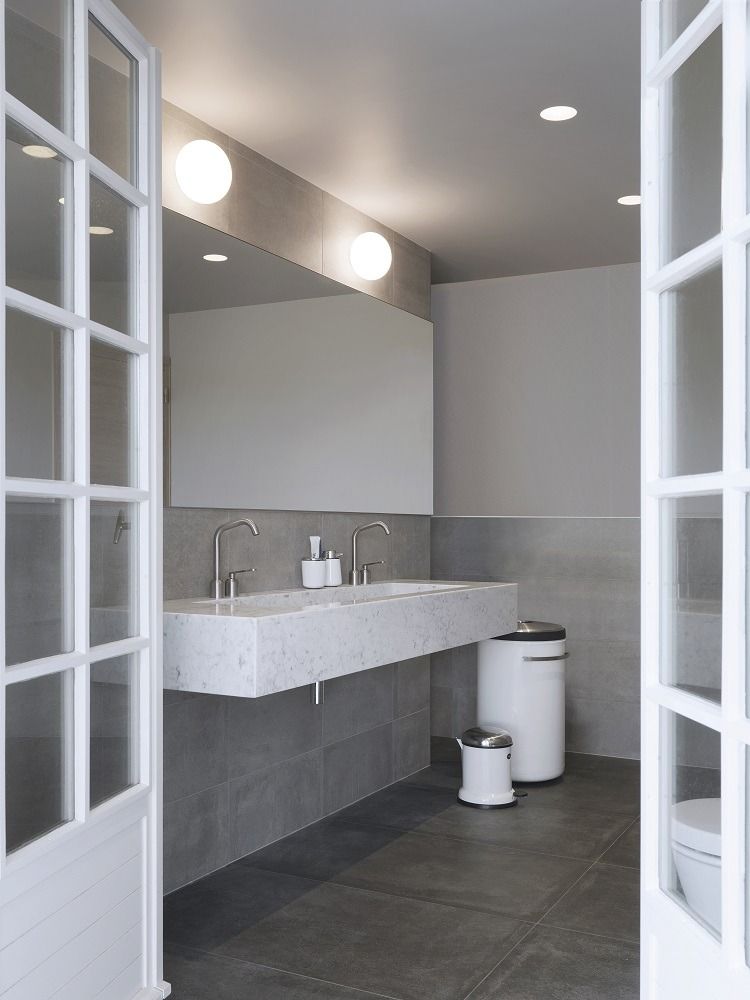 Helles Badezimmer mit modernem Marmorwaschtisch und weißem Vipp Wäschekorb sowie kleinem Treteimer.