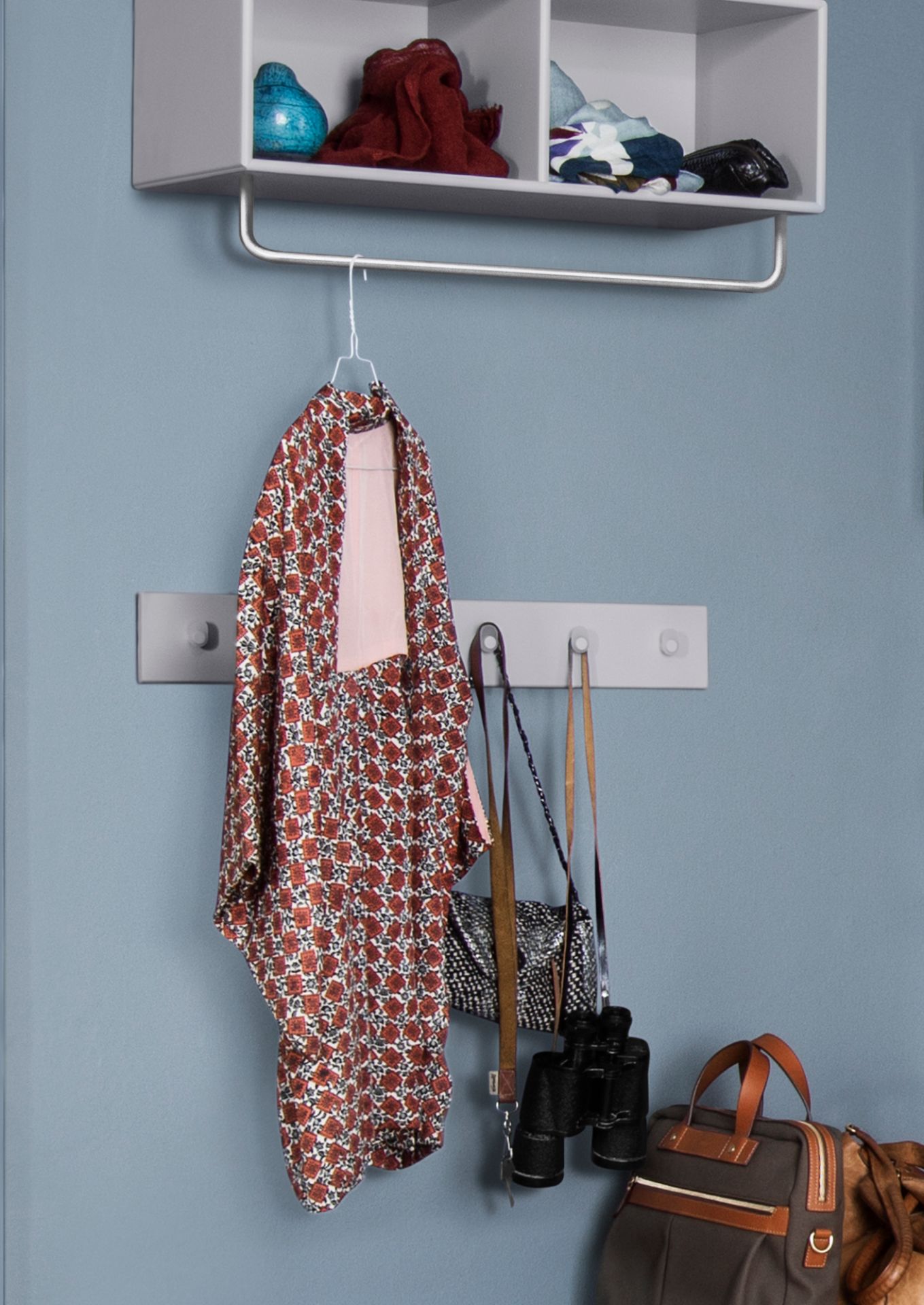 Montana Coat Ablage mit Kleiderstange in Mushroom: Ablage mit Kleidung, Taschen und Dekoration an blauer Wand.