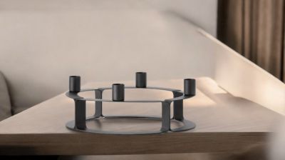 Schwarzer Lucca Kerzenständer von novoform für vier Kerzen auf einem Holztisch.