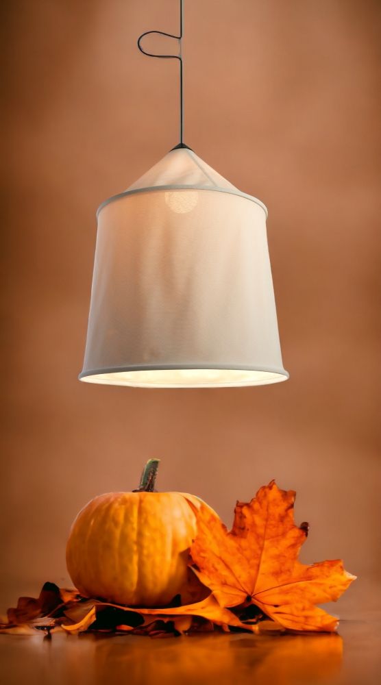 Beige Jaima Pendelleuchte für den Außenbereich über Kürbis und Herbstlaub. Marset Outdoor Lampe.