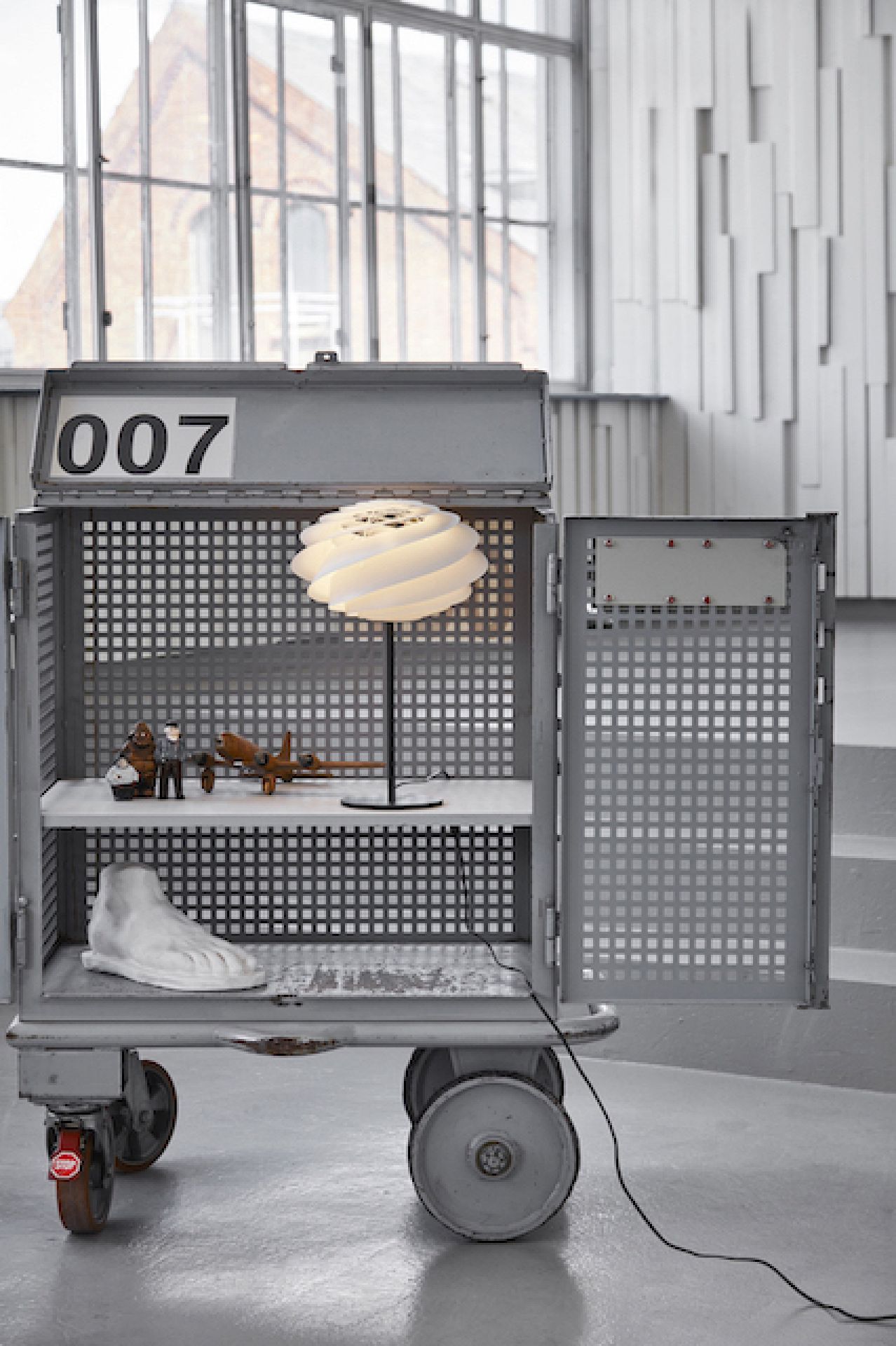 Swirl Tischleuchte von Le Klint auf einem Regal. Design Lampe mit spiralförmigem Lampenschirm.