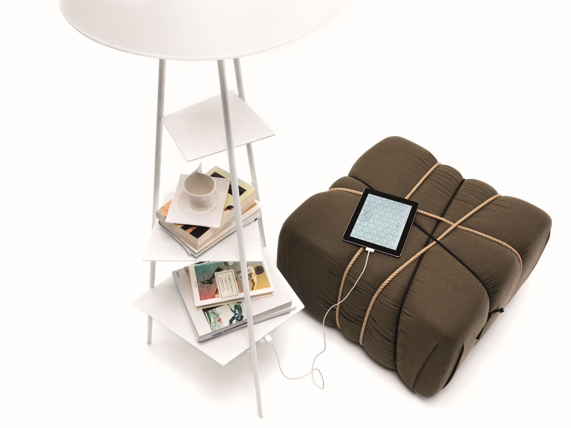 Weiße Tribeca Stehlampe von Mogg mit Ablageflächen und ein Tablet auf einem braunen Sitzkissen.