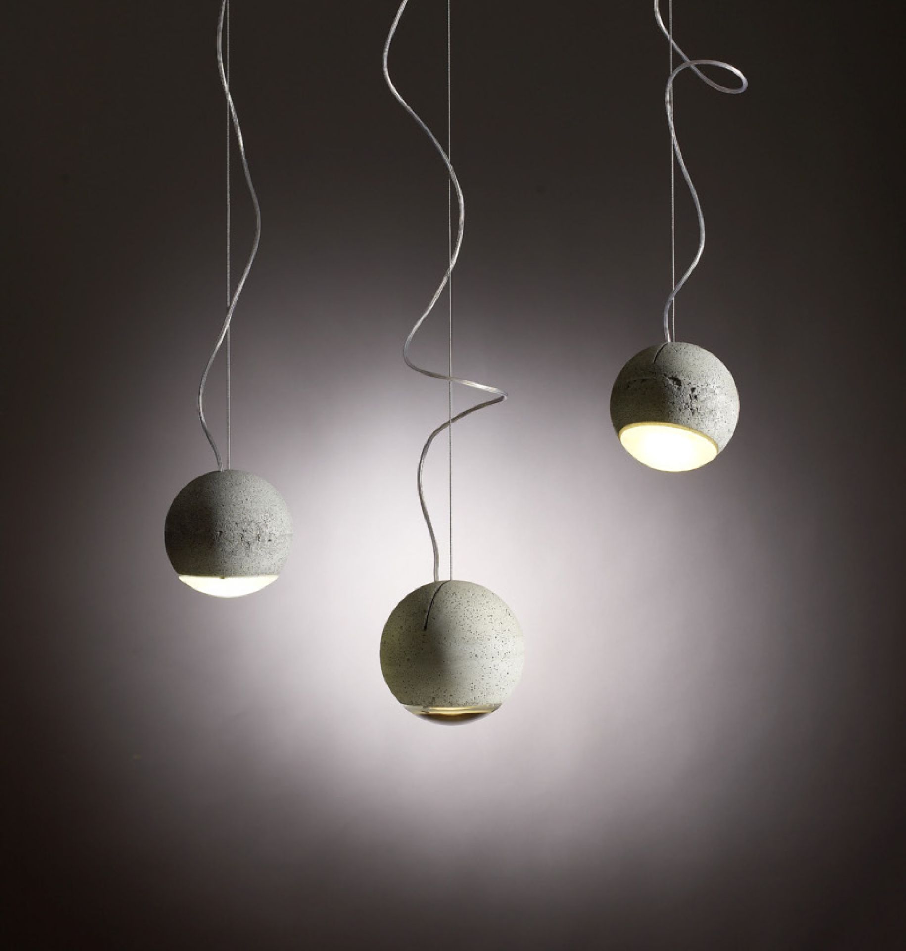 Trabant 2 Pendelleuchte von Tecnolumen: Drei moderne Hängelampen mit runden, grauen Betonschirmen und gewundenen Kabeln.
