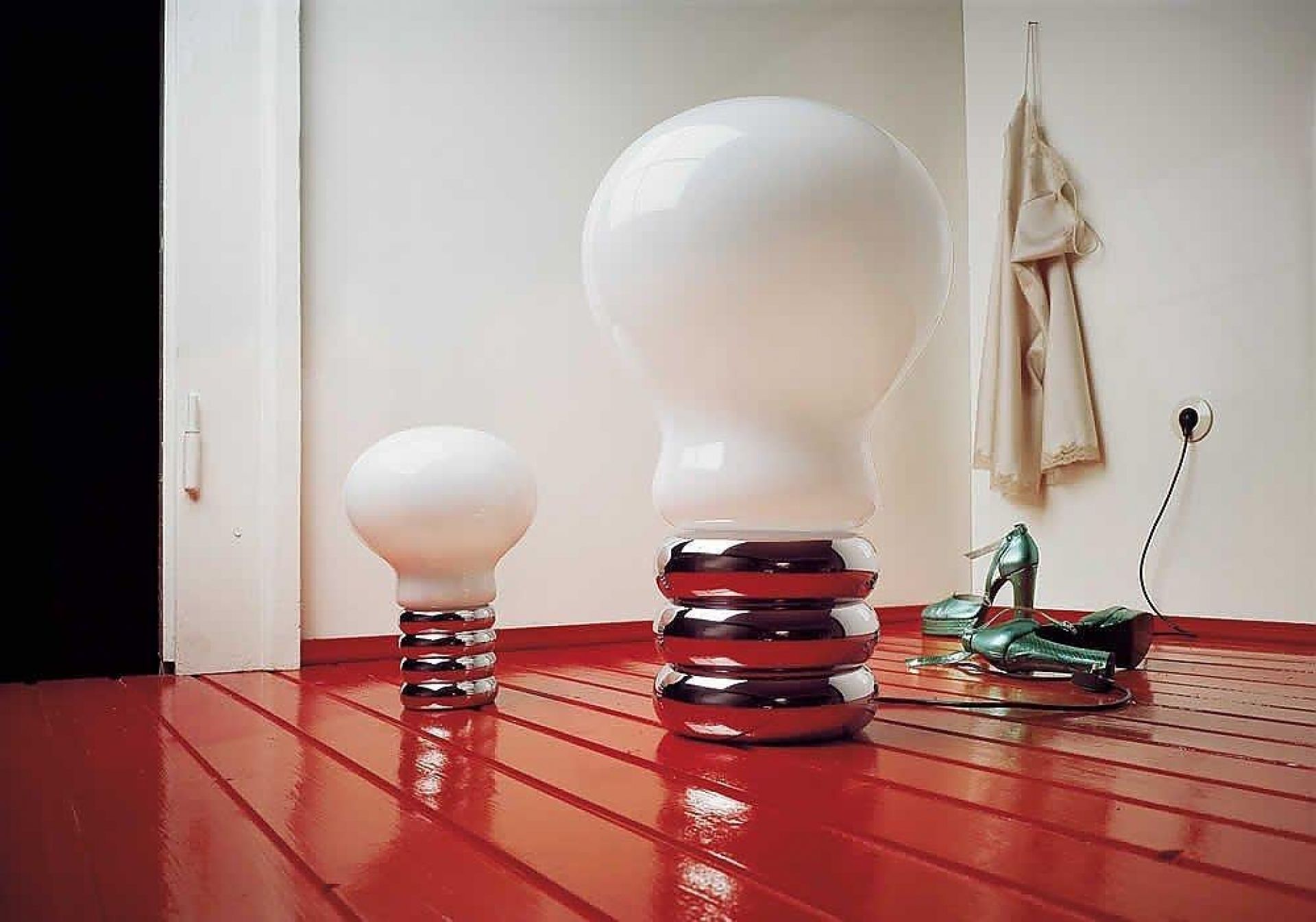 Zwei Bulb Tischleuchten von Ingo Maurer, Designleuchten im Glühbirnen-Design mit Chromfuß auf rotem Boden.