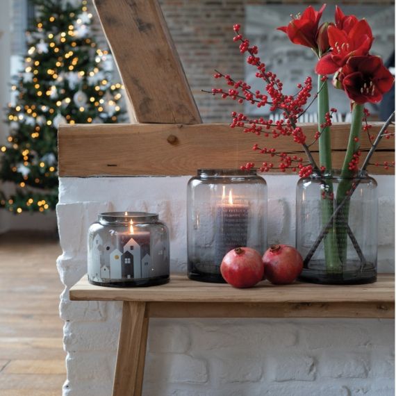 Winterliche Dekoration mit Räder Winterlicht Häuser Windlicht, roten Blumen und Granatäpfeln auf Holzbank.