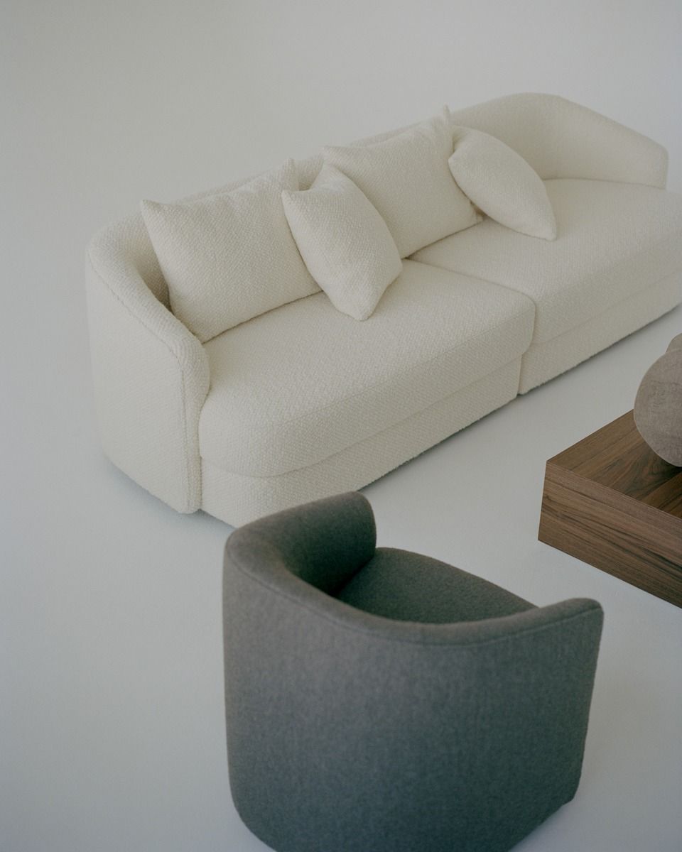 Helles Covent Sofa von New Works mit Kissen und grauem Sessel für Wohnzimmer.
