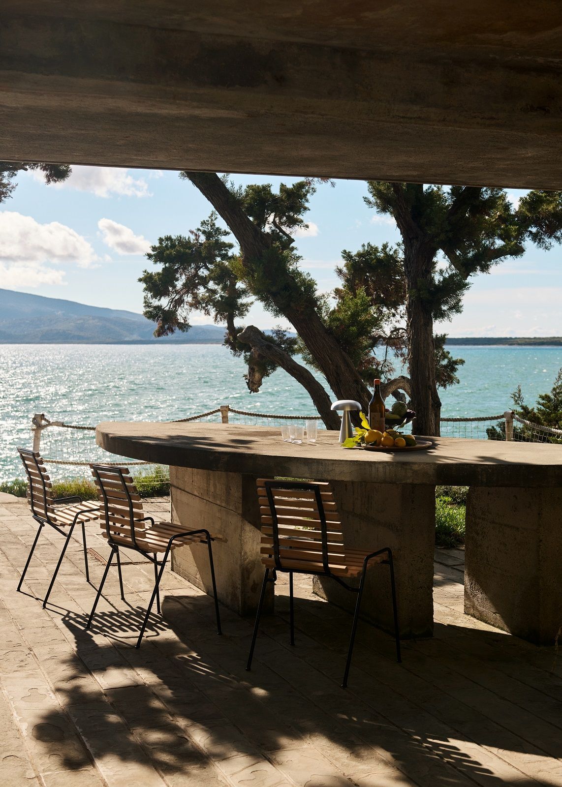 RFH Robin Day RD4 Outdoor Dining Chair von AndTradition am Esstisch mit Meerblick.