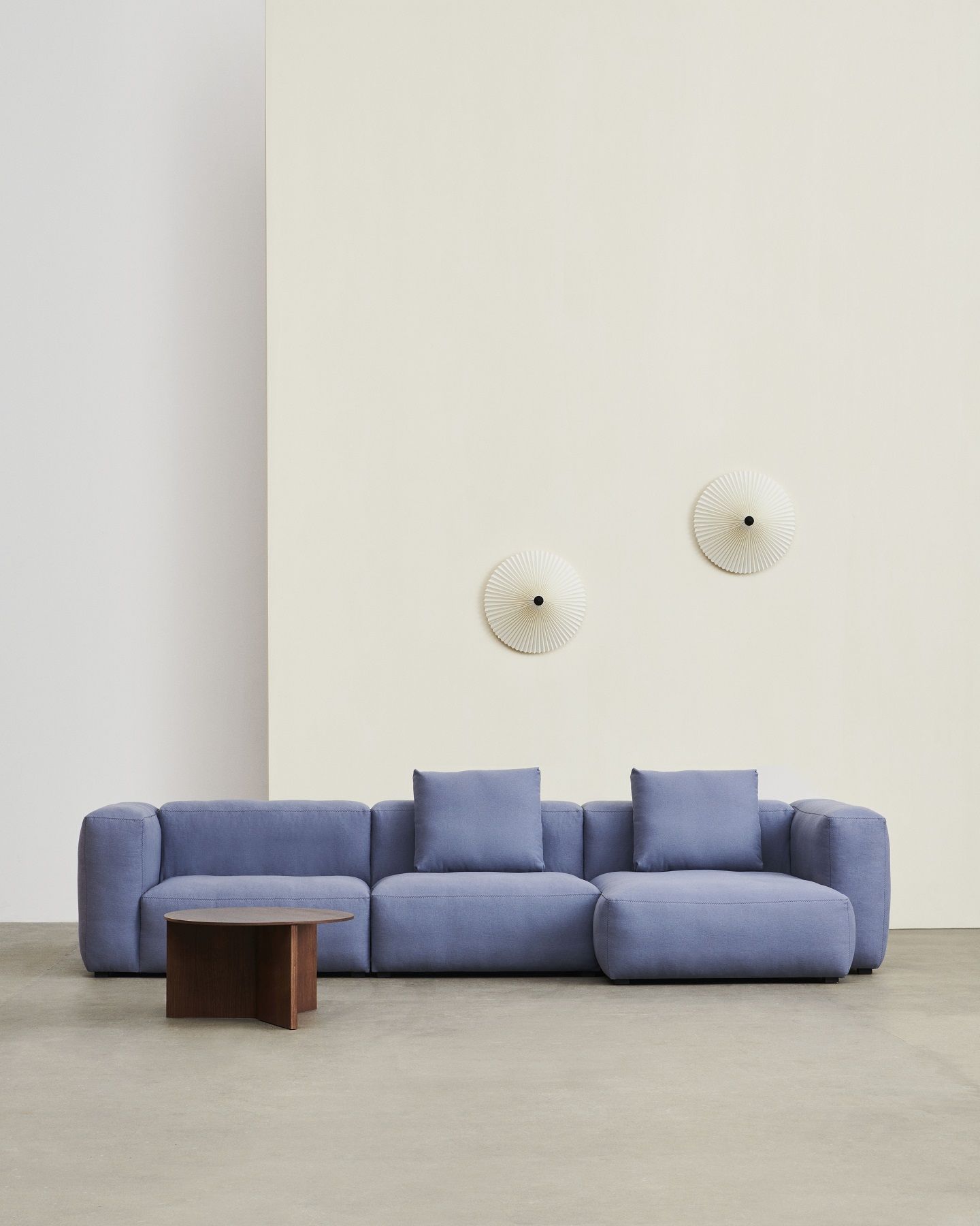 Hay Slit Table Wood Round XL, dunkler Holz-Beistelltisch vor blauem Sofa im minimalistischen Wohnzimmer.