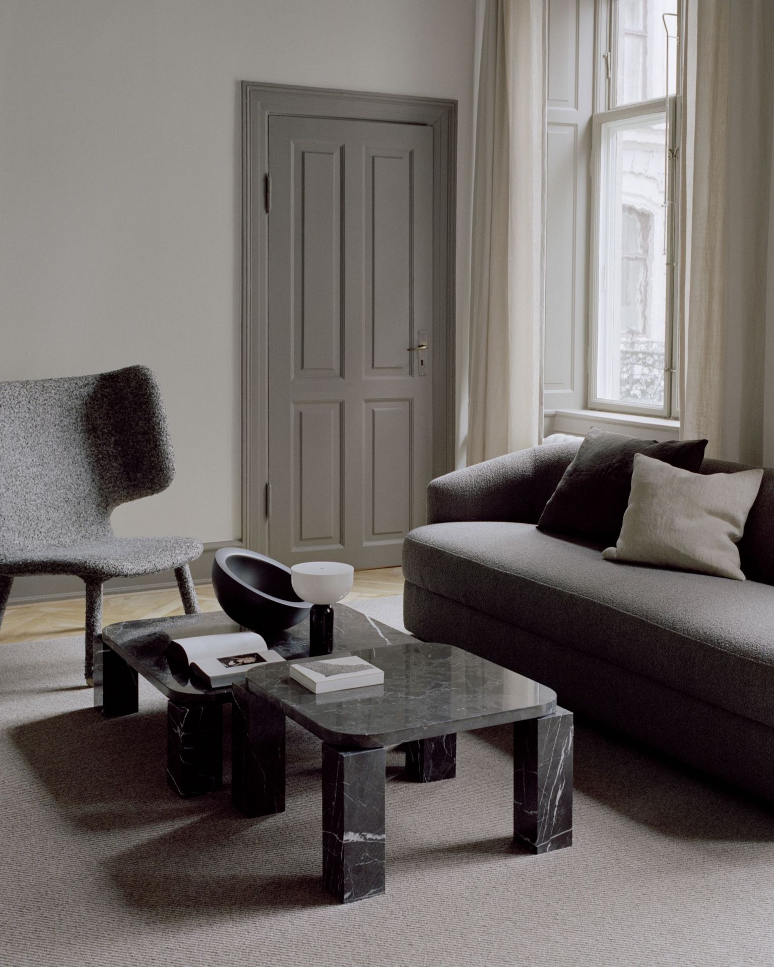 New Works Atlas Couchtisch 600x600 Costa Schwarz im Wohnzimmer mit Sofa und Sessel.