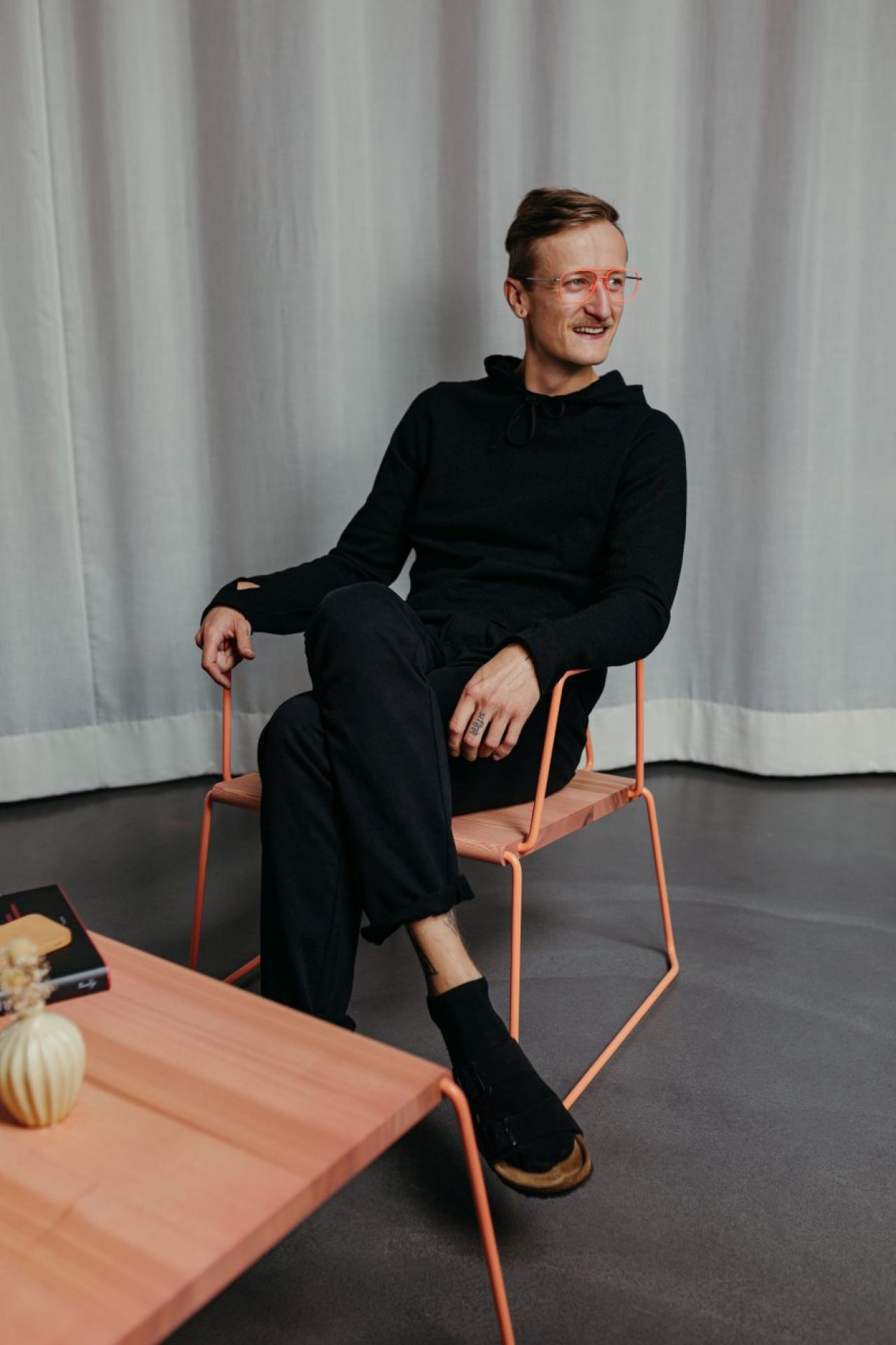 Mann sitzt entspannt im D:008 Loungechair von Fuchs & Habicht. Kohleschwarzer Sessel mit Armlehnen.