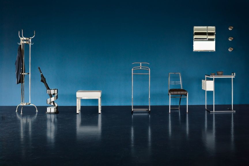 Nymphenburg Coat Stand Garderobenständer ClassiCon aus Nickel, mit weiteren Möbeln vor blauem Hintergrund.