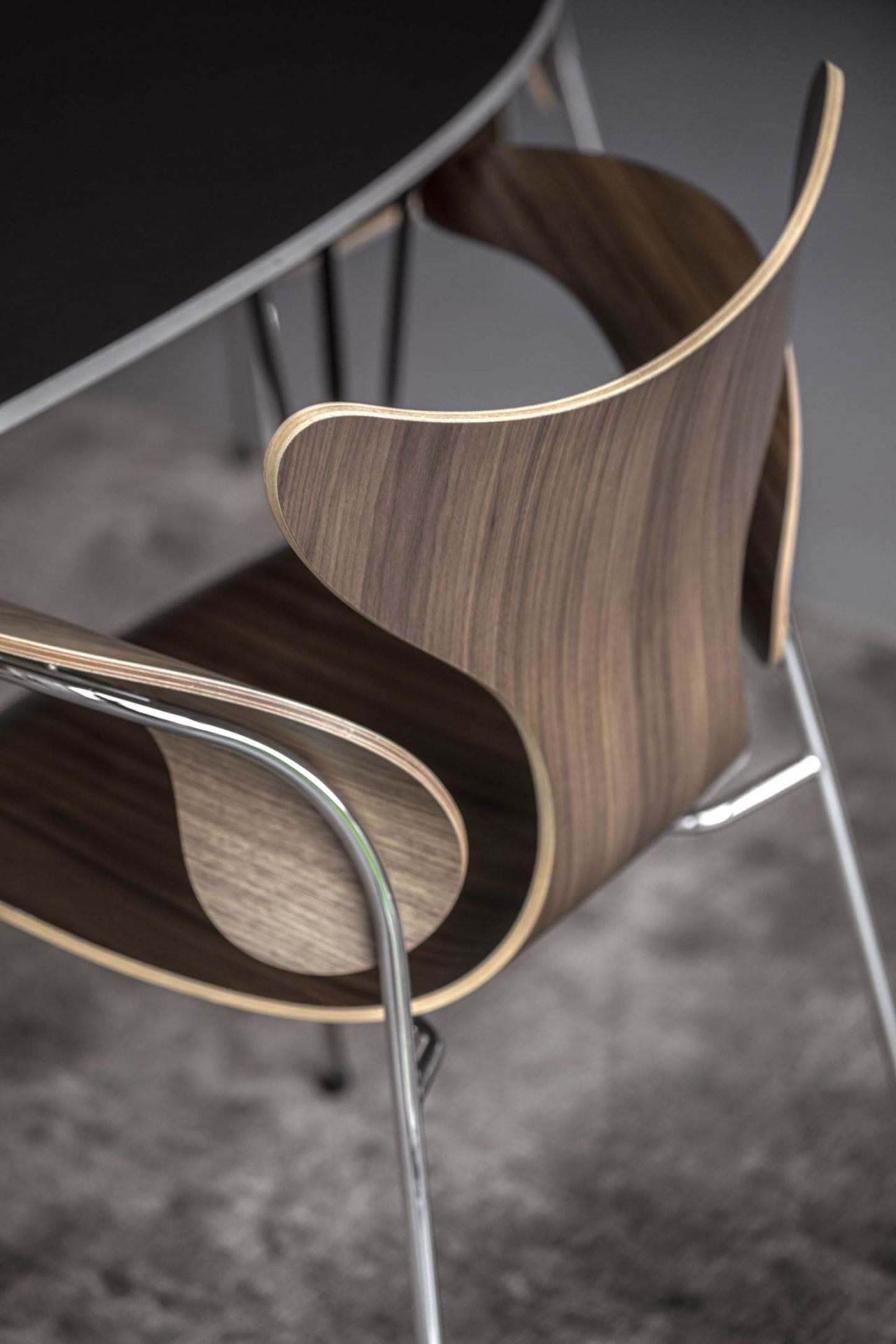 Detailaufnahme des Fritz Hansen Lily Stuhls mit Armlehnen, Holzschale und Chromgestell. Designklassiker für Esszimmer.