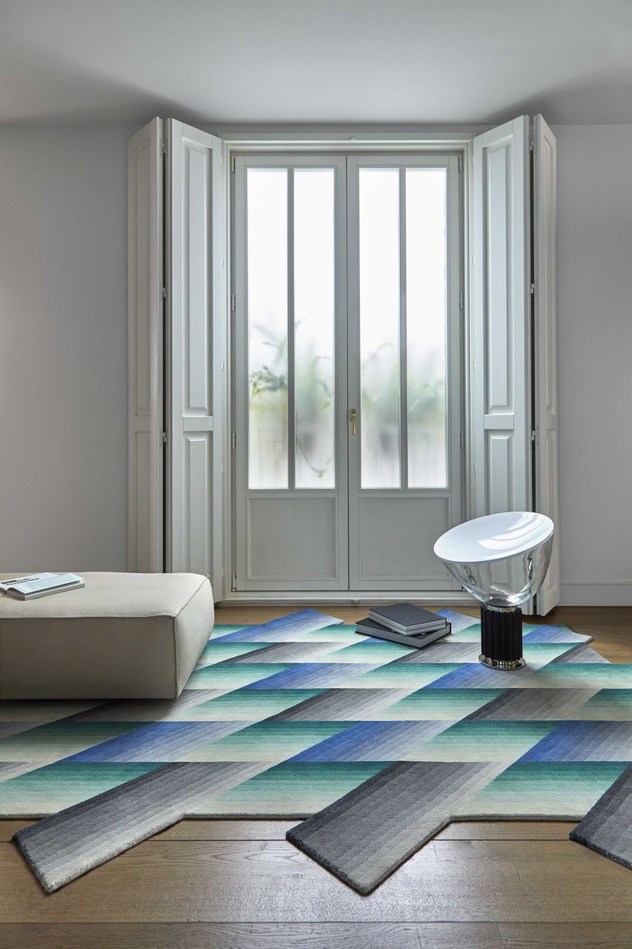 Wohnzimmer mit blauem Mirage Teppich von Gan, geometrisches Muster, moderne Einrichtung und hellem Holzboden.