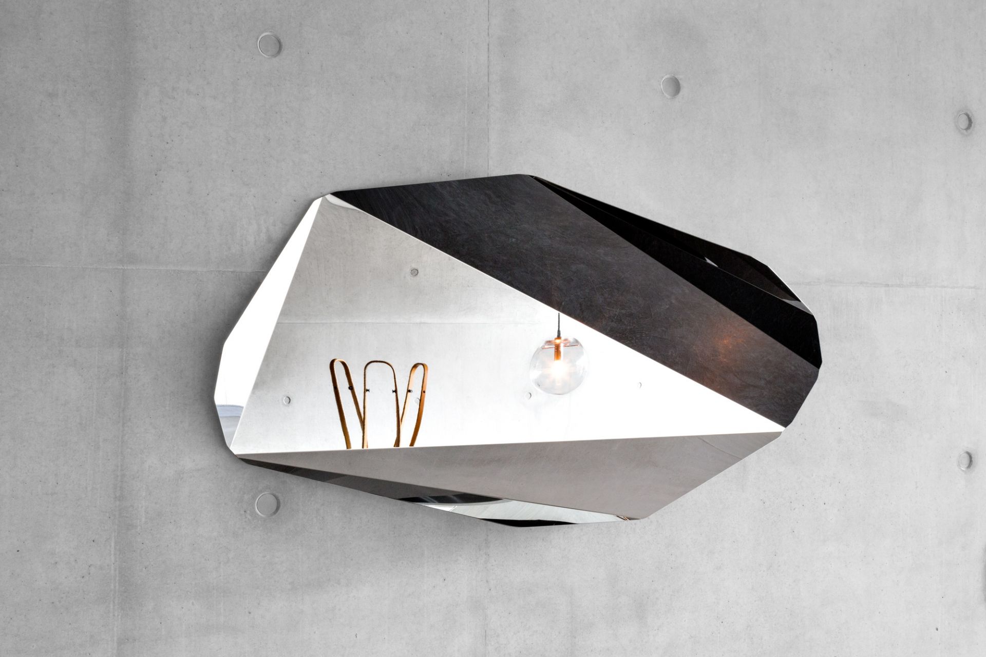 Piega Mirror Wandspiegel von Classicon, großer, facettenreicher Design-Spiegel an einer Betonwand. Modernes Wohnaccessoire.