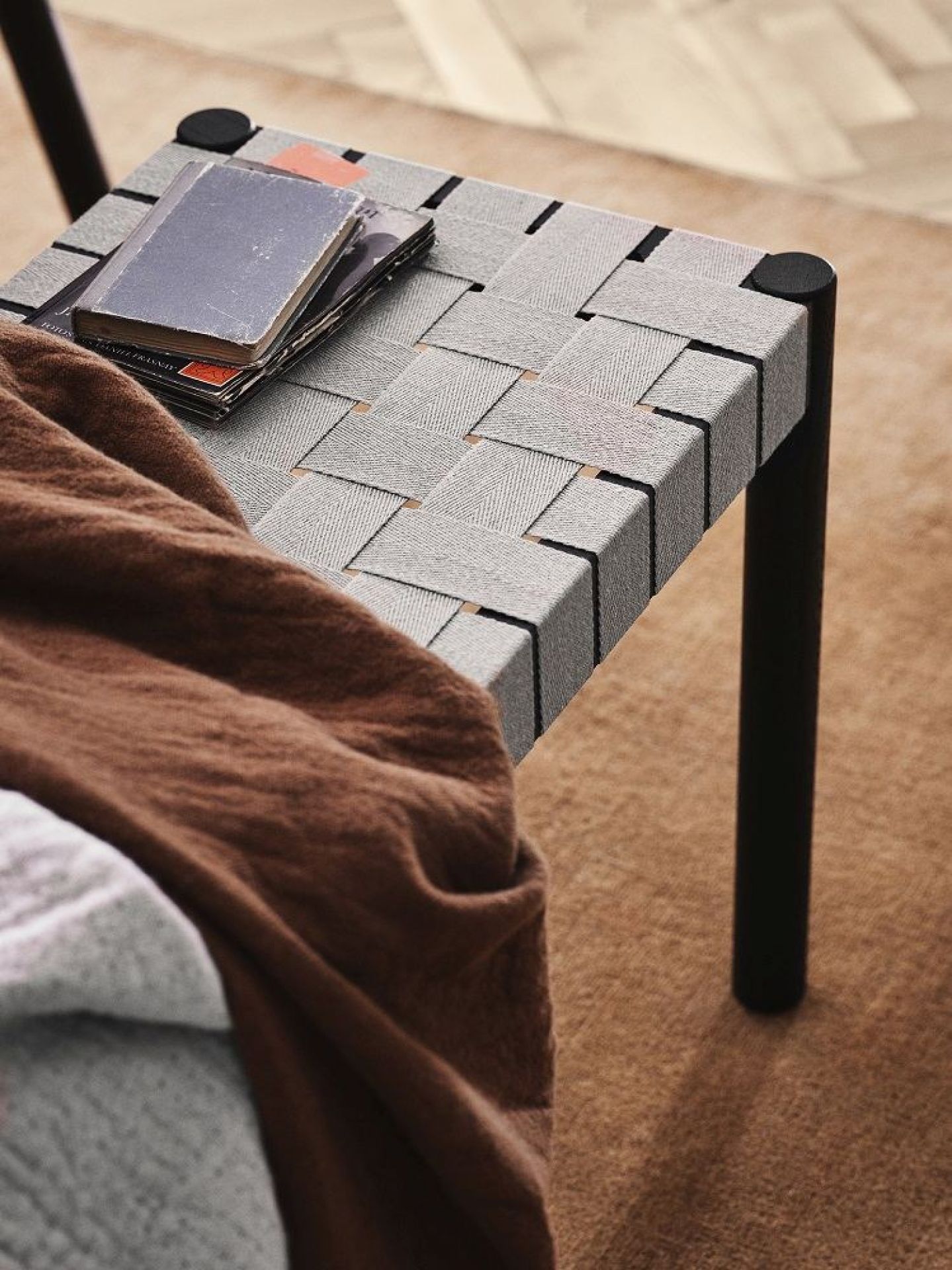 Detailaufnahme der AndTradition Betty Bank mit gewebter Sitzfläche und Büchern.