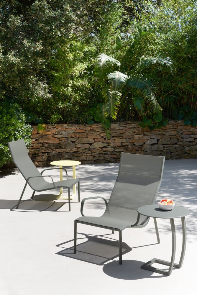 Cadiz Lounge Sessel von Fermob im Außenbereich mit Beistelltisch und tropischer Bepflanzung.