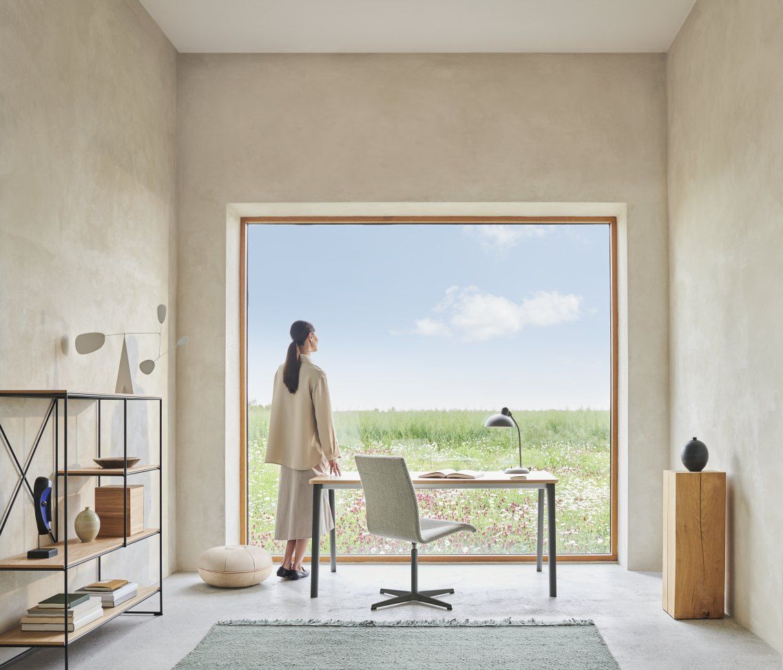Heller Raum mit Fritz Hansen Tisch, Stuhl und Frau am Fenster. Moderner Schreibtisch.
