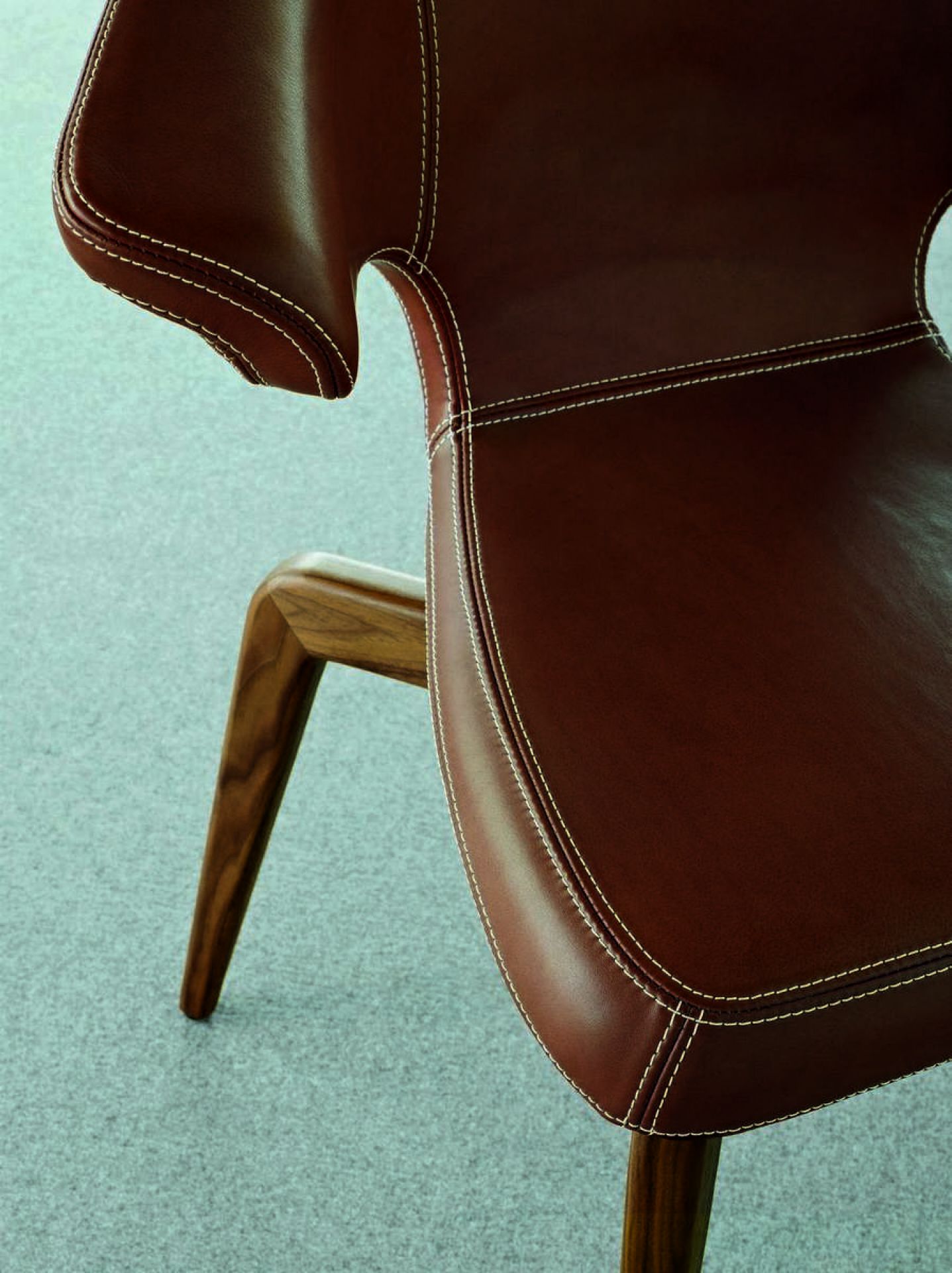 Detailaufnahme: Munich Armchair Stuhl mit braunem Lederbezug und Holzbeinen, hochwertige Designermöbel.
