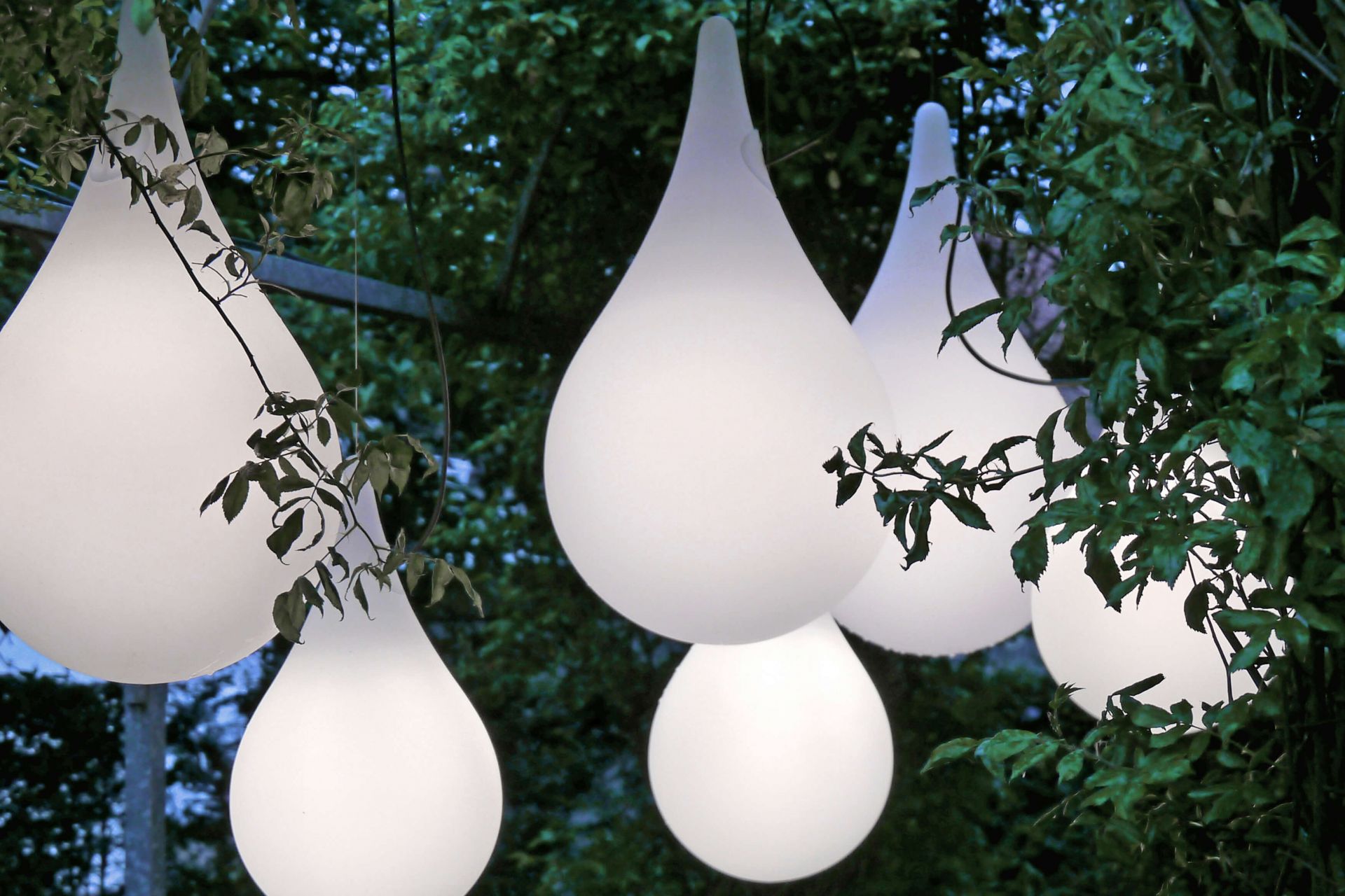Mehrere Liquid Light Drop Pendelleuchten von Next im Außenbereich, umgeben von Grün.