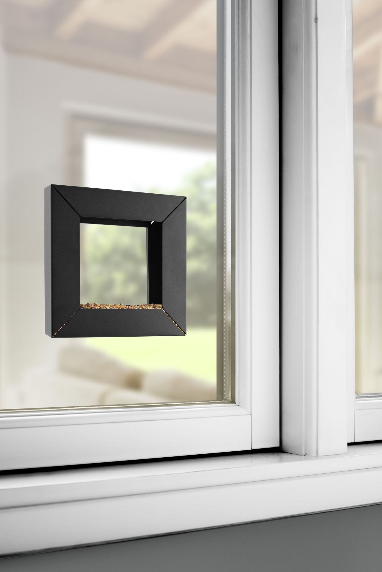 Schwarzer Eva Solo Rahmen Futterspender am Fenster mit Vogelfutter, modernes Design für Wildvögel.