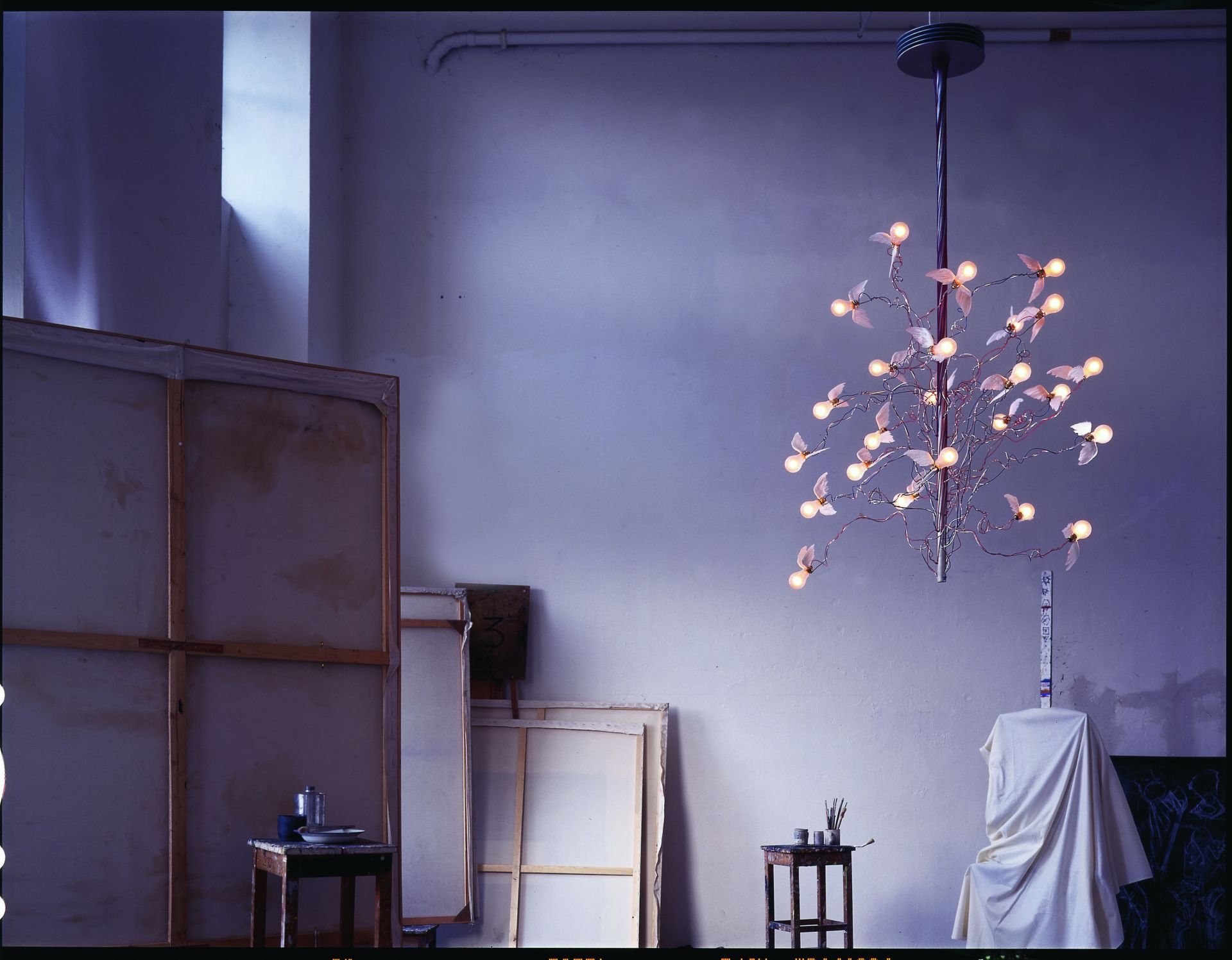 Birds Birds Birds Kronleuchter von Ingo Maurer: Hängelampe mit Glühbirnen und kleinen Flügeln im Atelier.