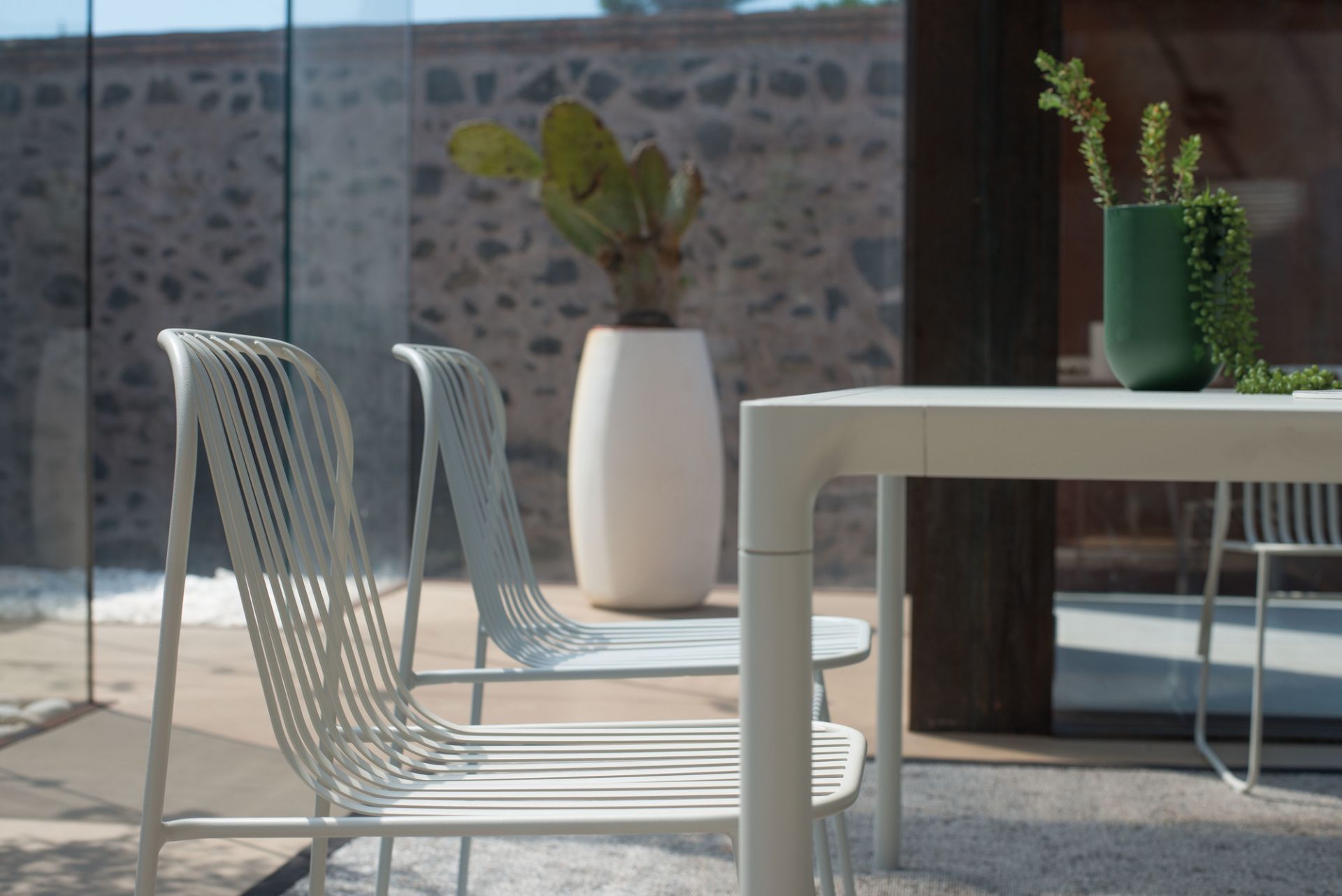 Riviera Stuhl in Antikes Eisen: Detailaufnahme von zwei modernen Metallstühlen für den Außenbereich.